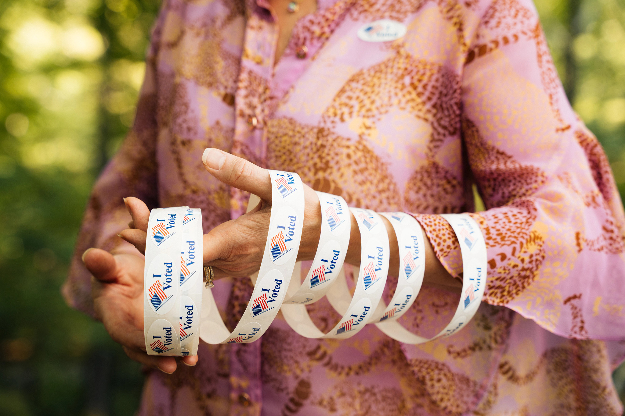 a hand holds i voted stickers with the american flag