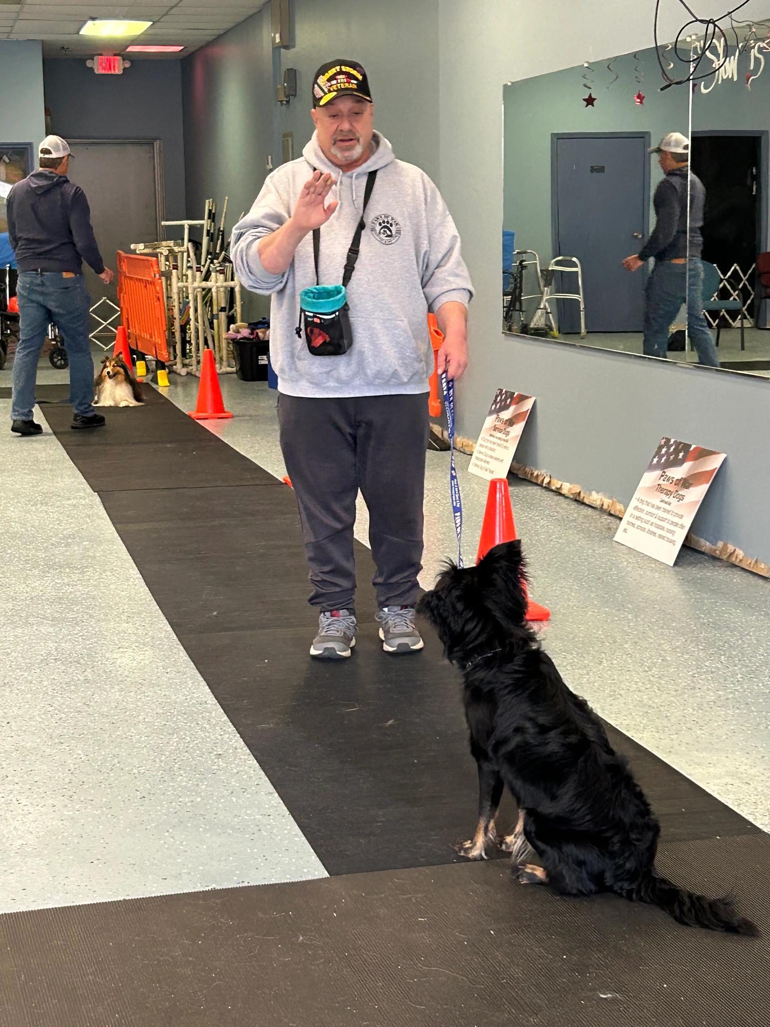 mike sweeney gives a command to his service dog, a black border collie mix