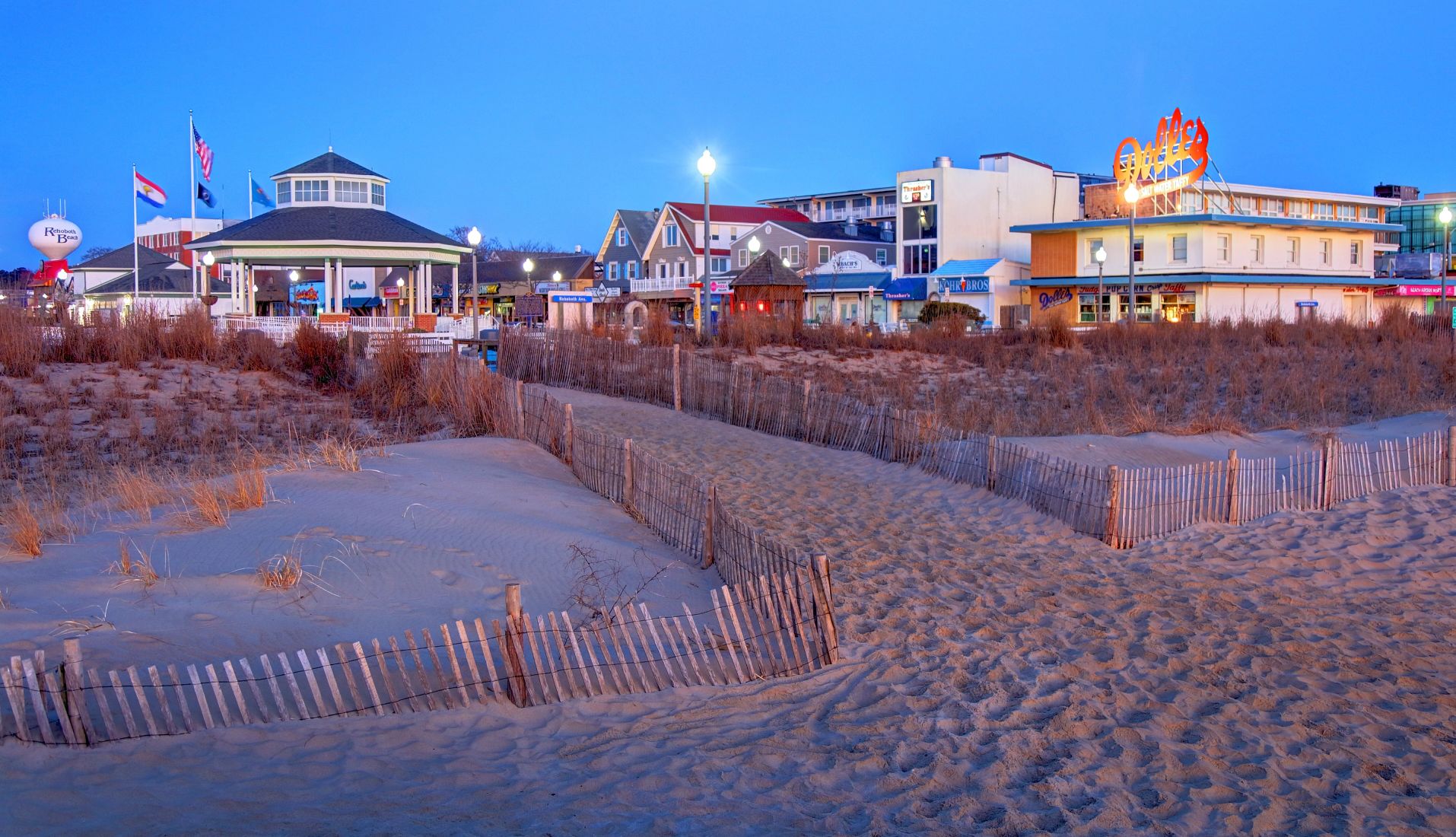 Beach Towns for Fall Getaways a beach in the foreground with a gazebo and stores in the background
