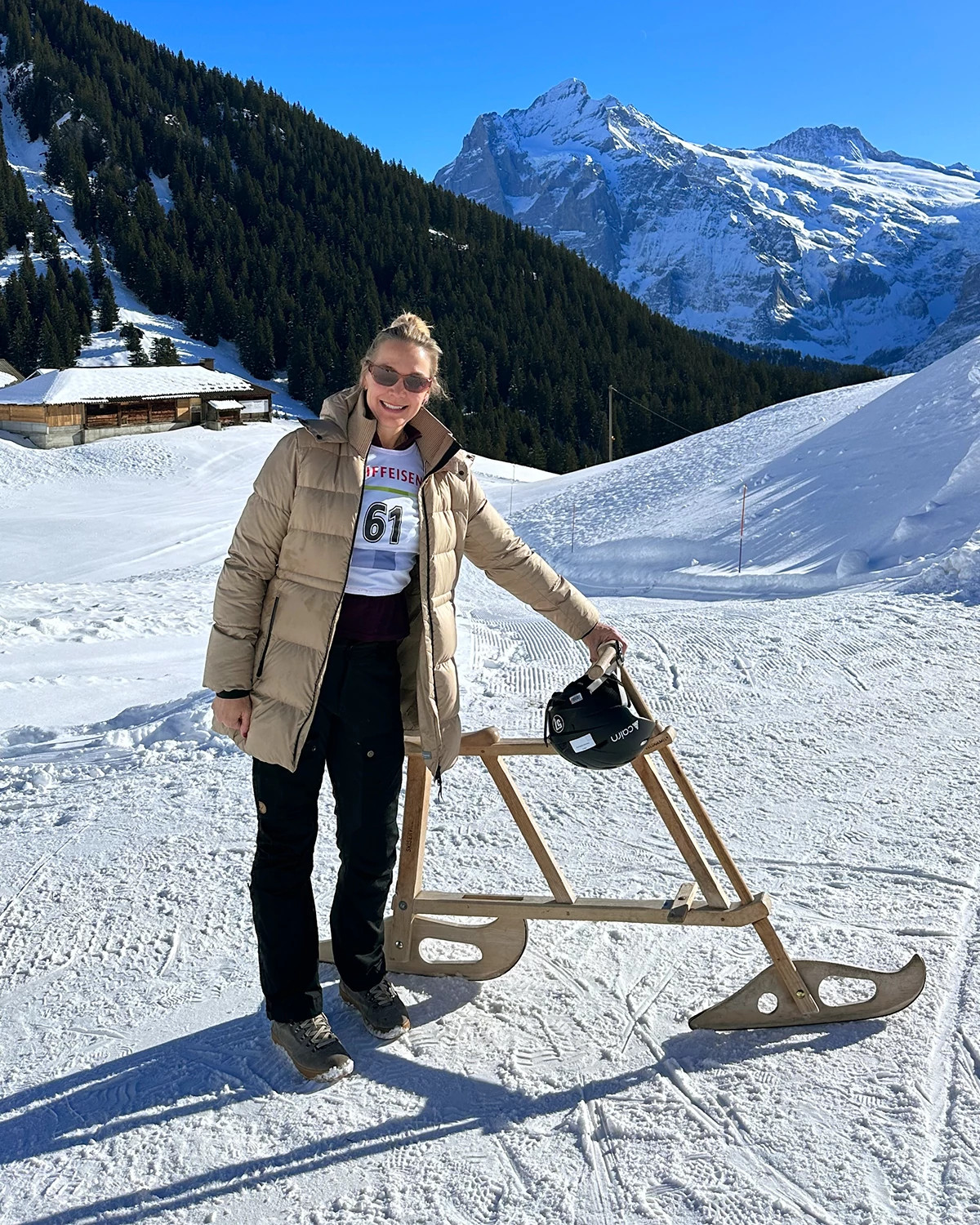 Woman in a snowy mountain scene beside her bike sled velogemel