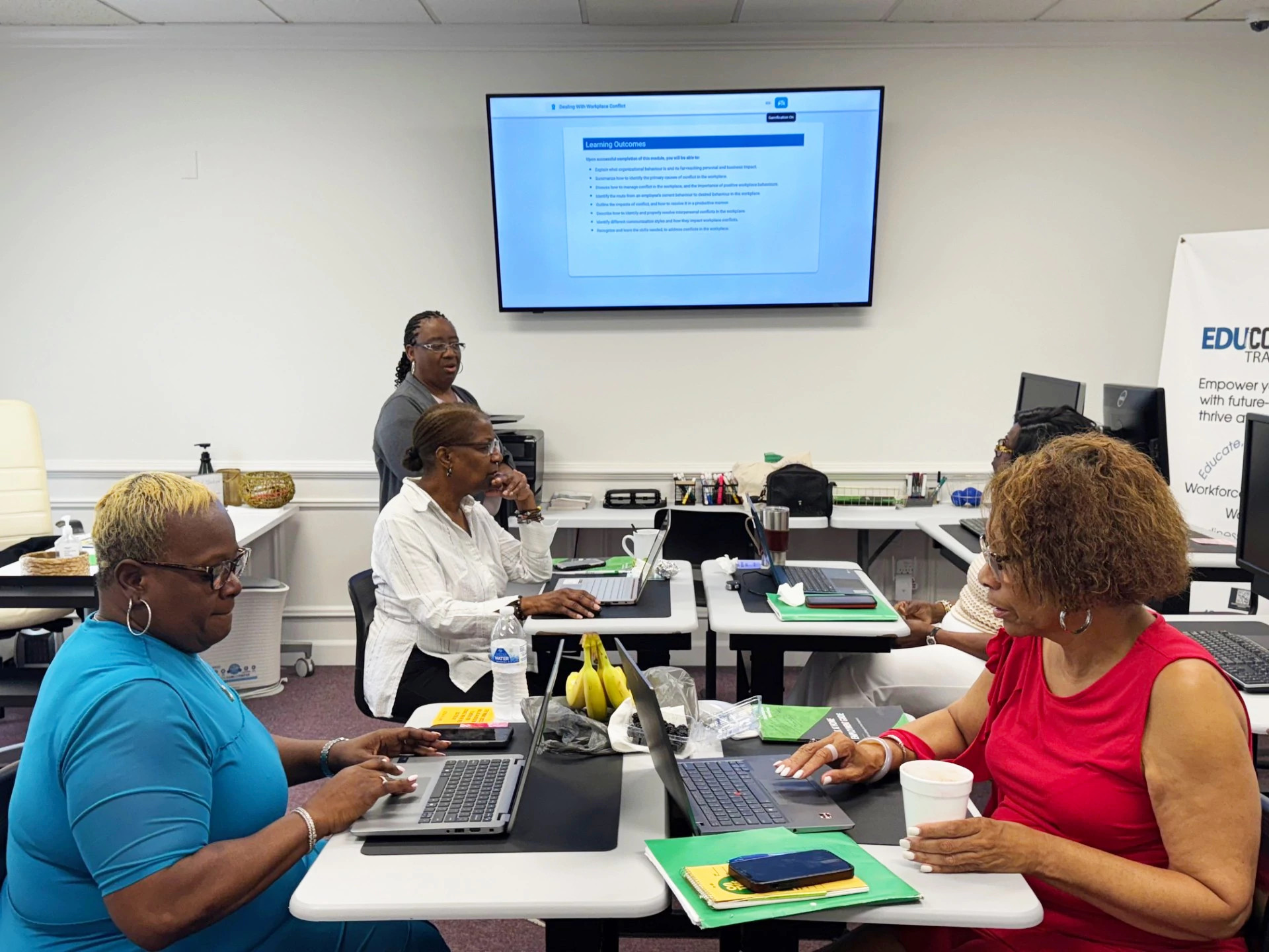 women working on laptops and talking in a room