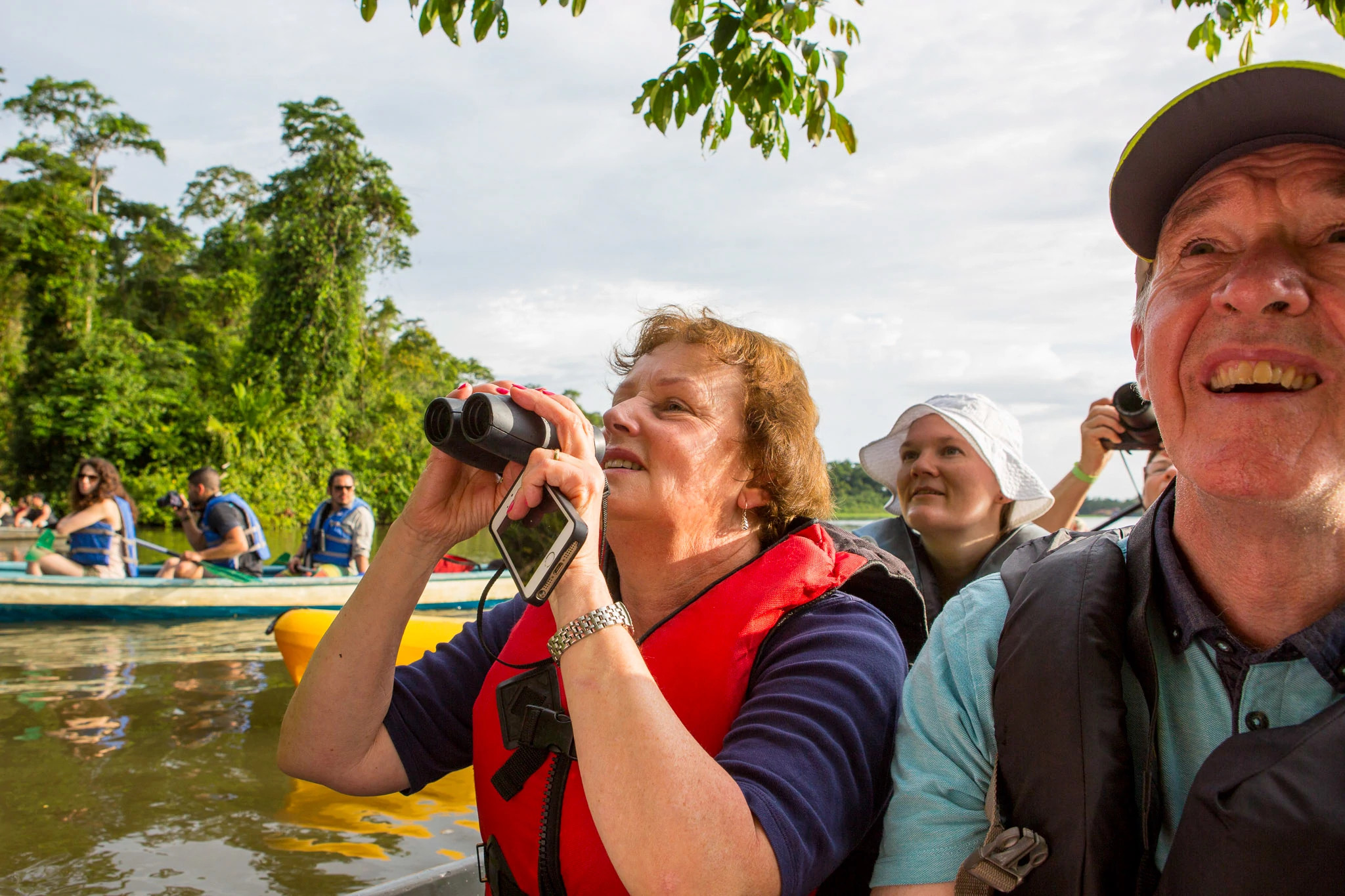 people birdwatching with binoculars and cameras on small boats