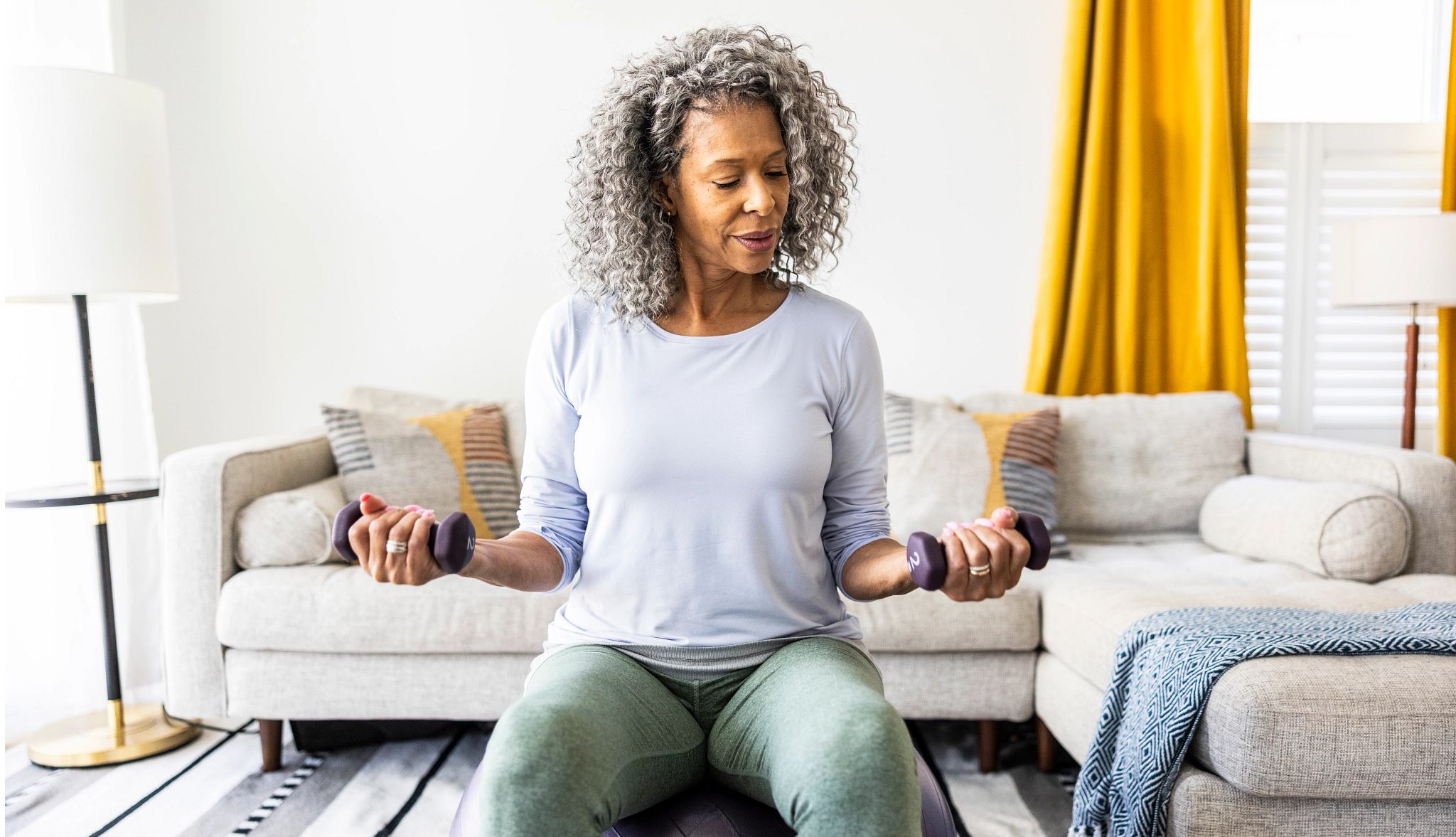 Senior woman lifting weights in living room Senior woman lifting weights in living room