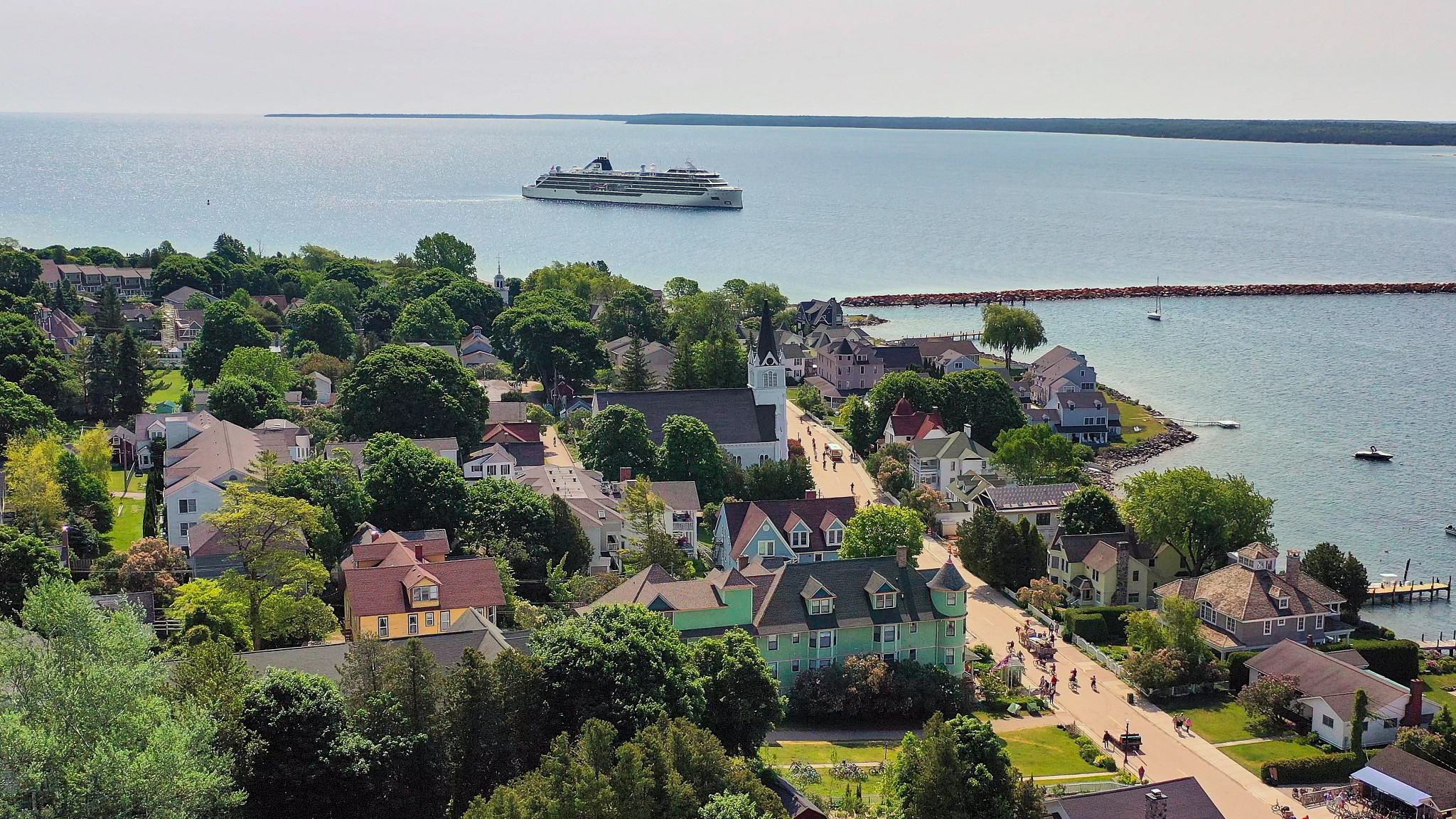an aerial view of a coastal town with a cruise ship in the distance