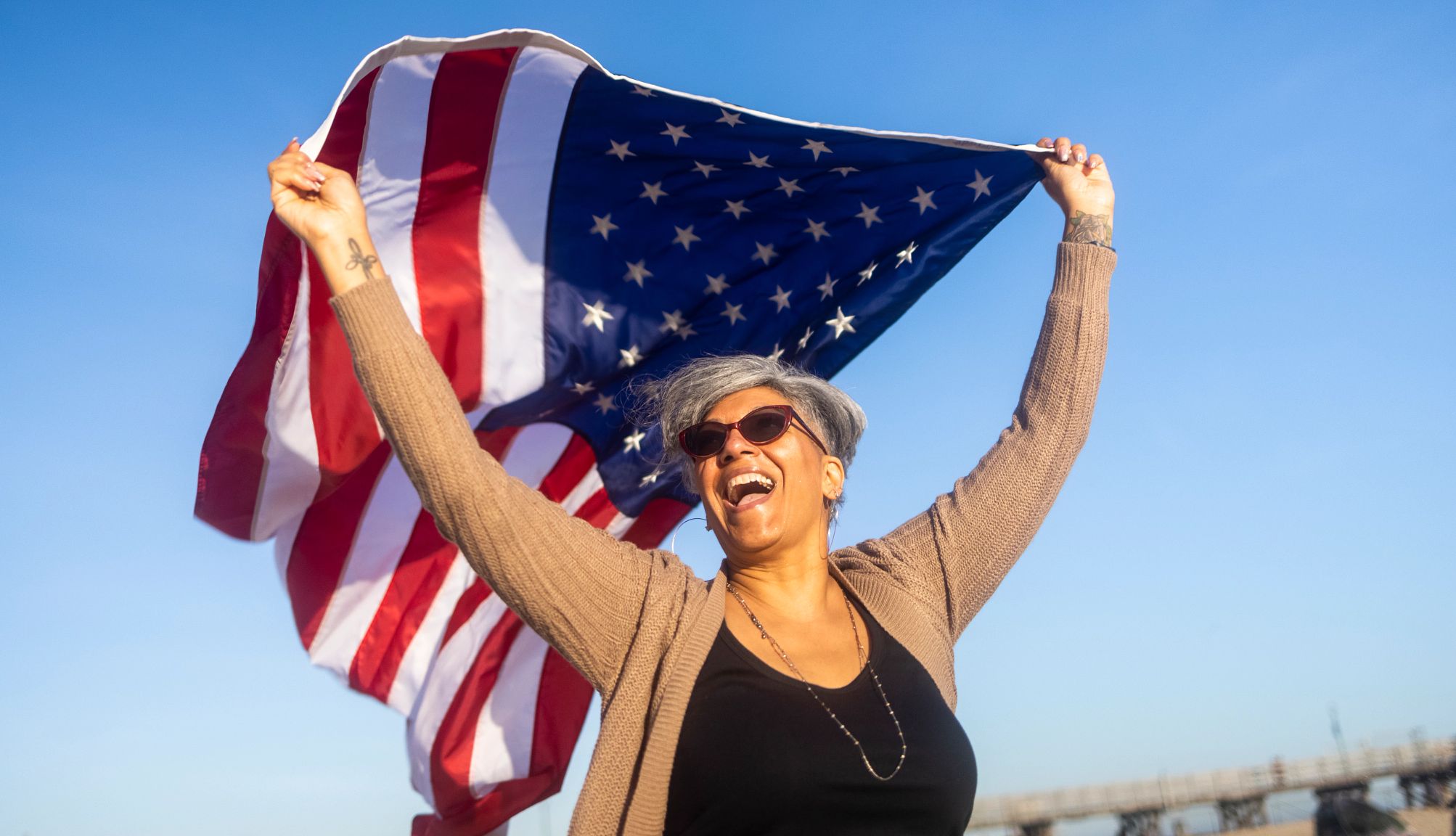 una mujer sonriente sostiene una bandera estadounidense