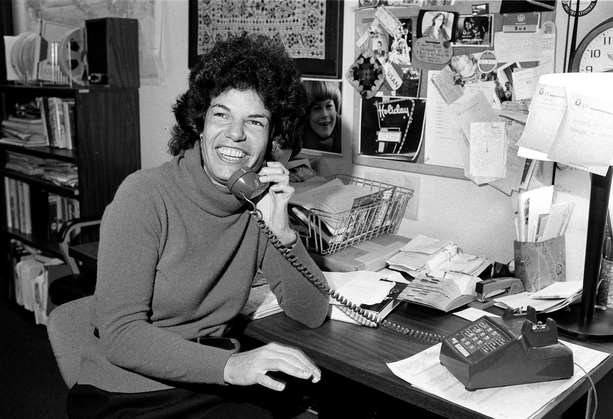 a young susan stamberg smiles as the speaks into a telephone