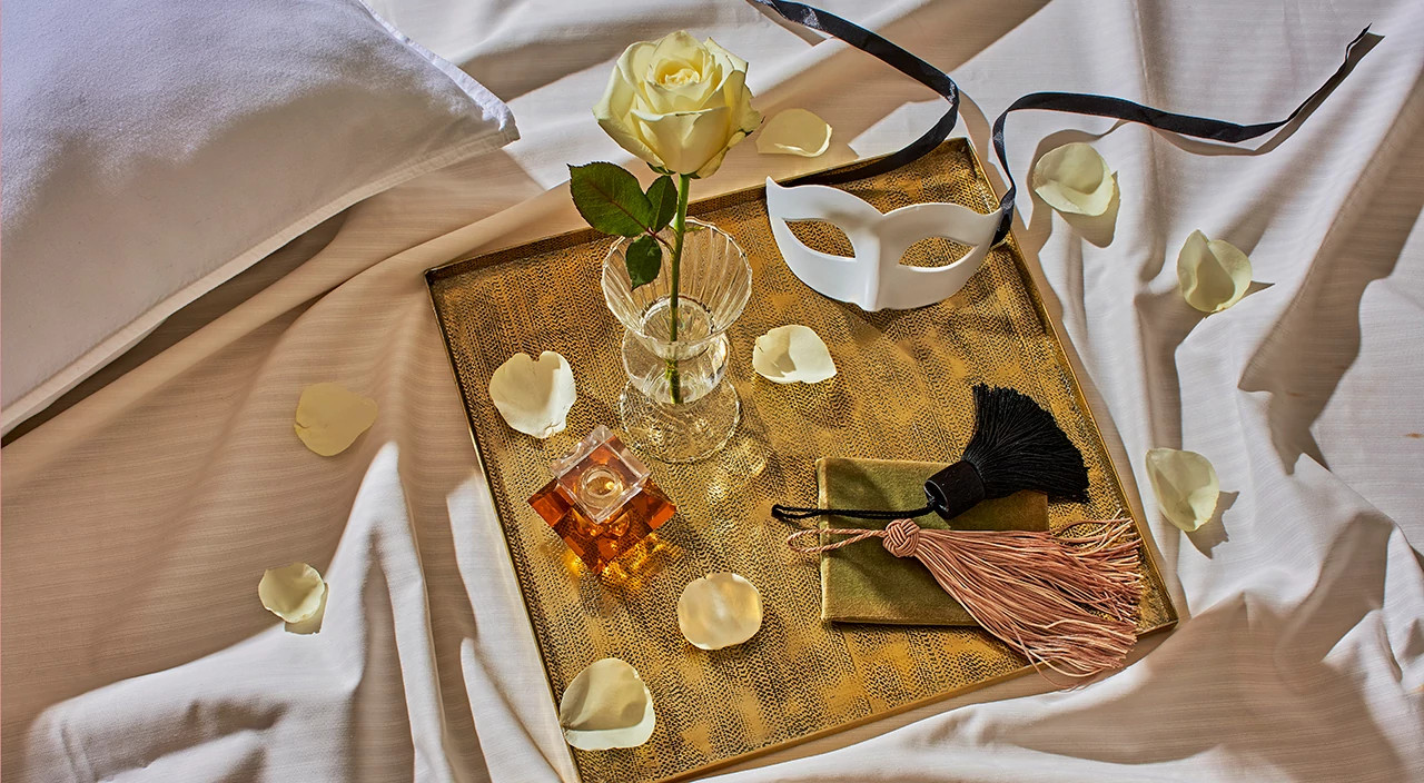 Tray of rose petals, mask and perfume.