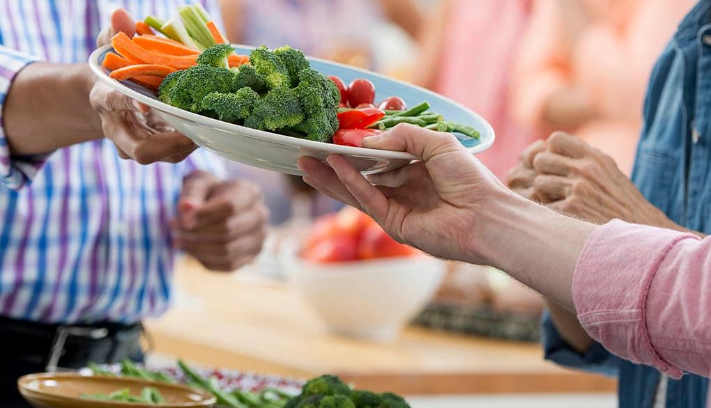 Eating fruits and vegetables may help you sleep better A person handing another person a plate of vegetables