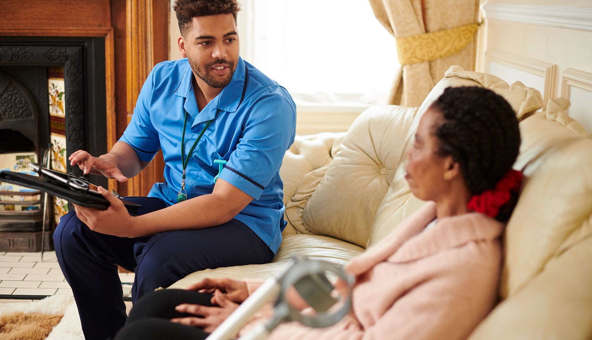 Male caregiver chatting with a senior client in her home male caregiver chatting with older woman on a couch