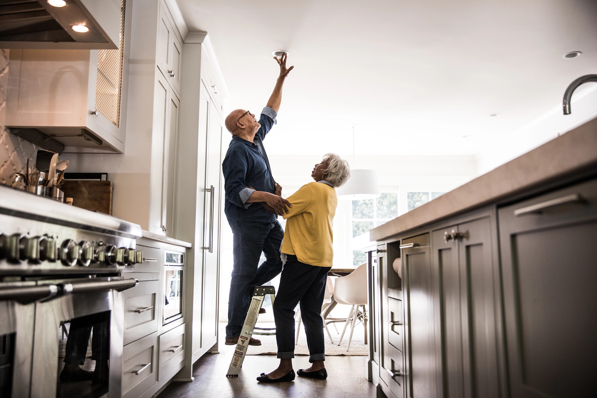 a man stands on a ladder while replacing a lightbulb in the ceiling
