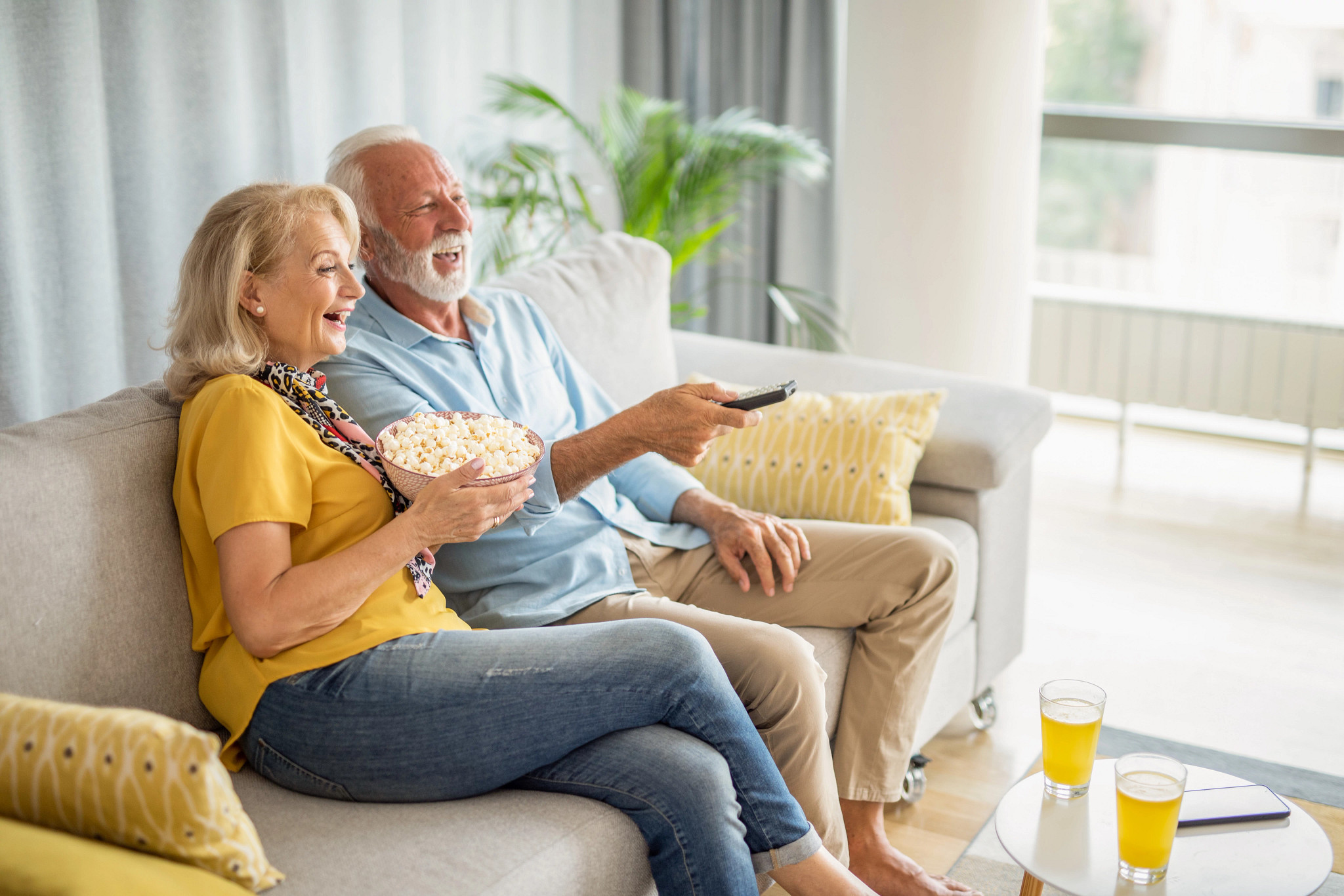 a couple sitting on a couch with a remote to watch tv