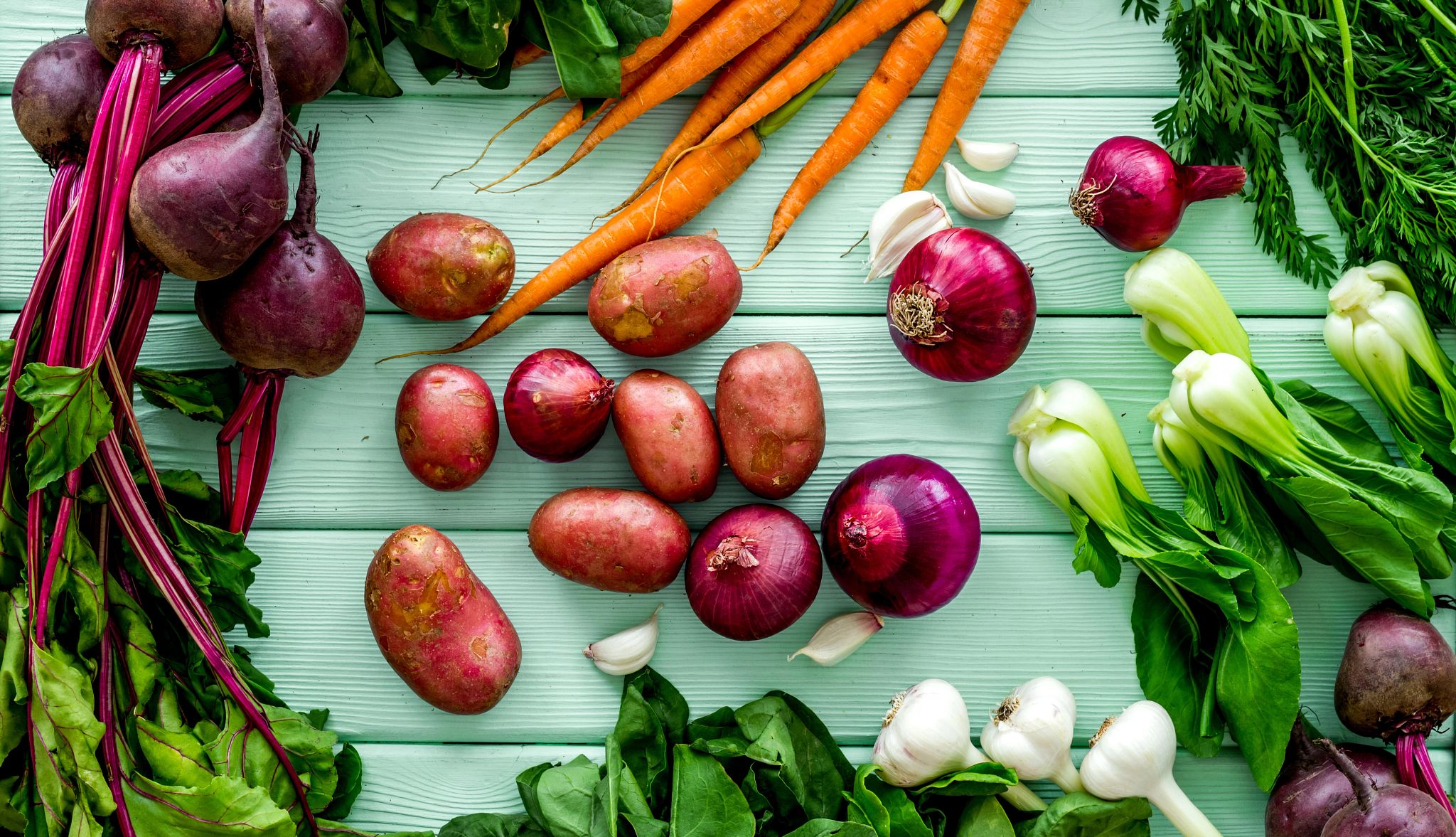 un surtido de verduras sobre un fondo color turquesa