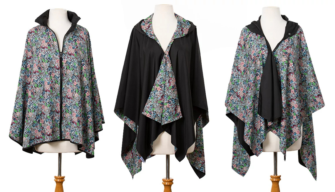 Three reversible rain ponchos displayed on mannequins, showing floral-print and solid-black sides