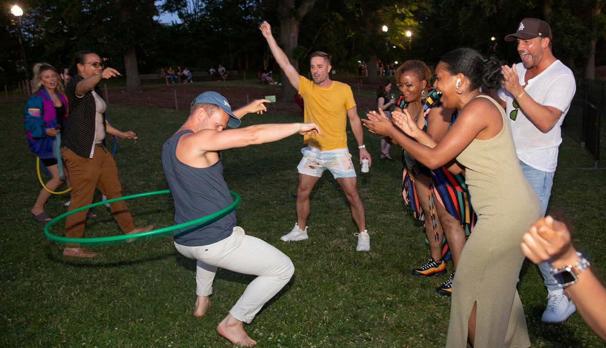 Un grupo de adultos baila con un hula hoop y se divierten
