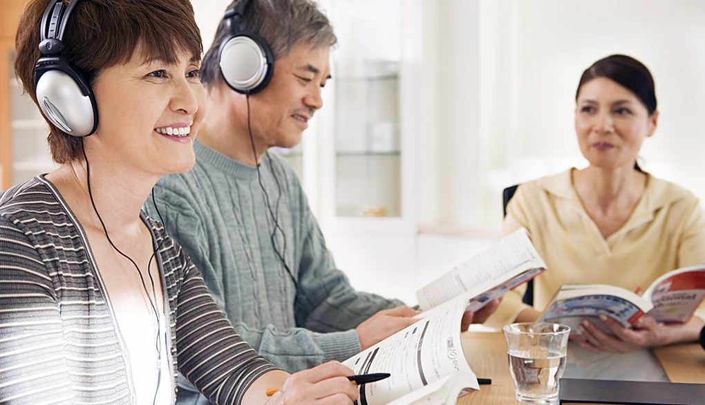 It's never too late to learn a second language A man and woman listening to something with headphones