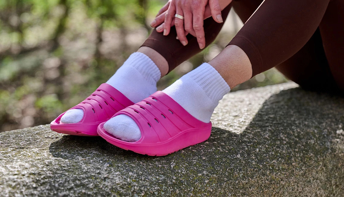 a person wearing fuschia shoes sitting on a rock outside