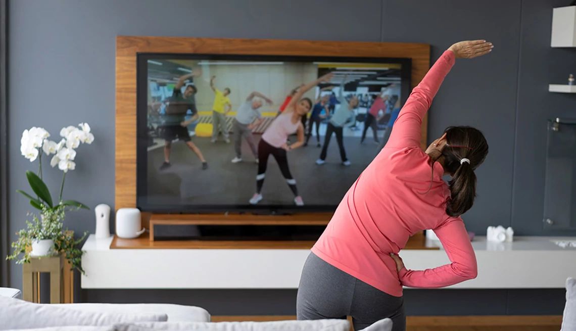 Engaging your mind can help you get off the couch Back view of a woman stretching as she watches an exercise class on TV