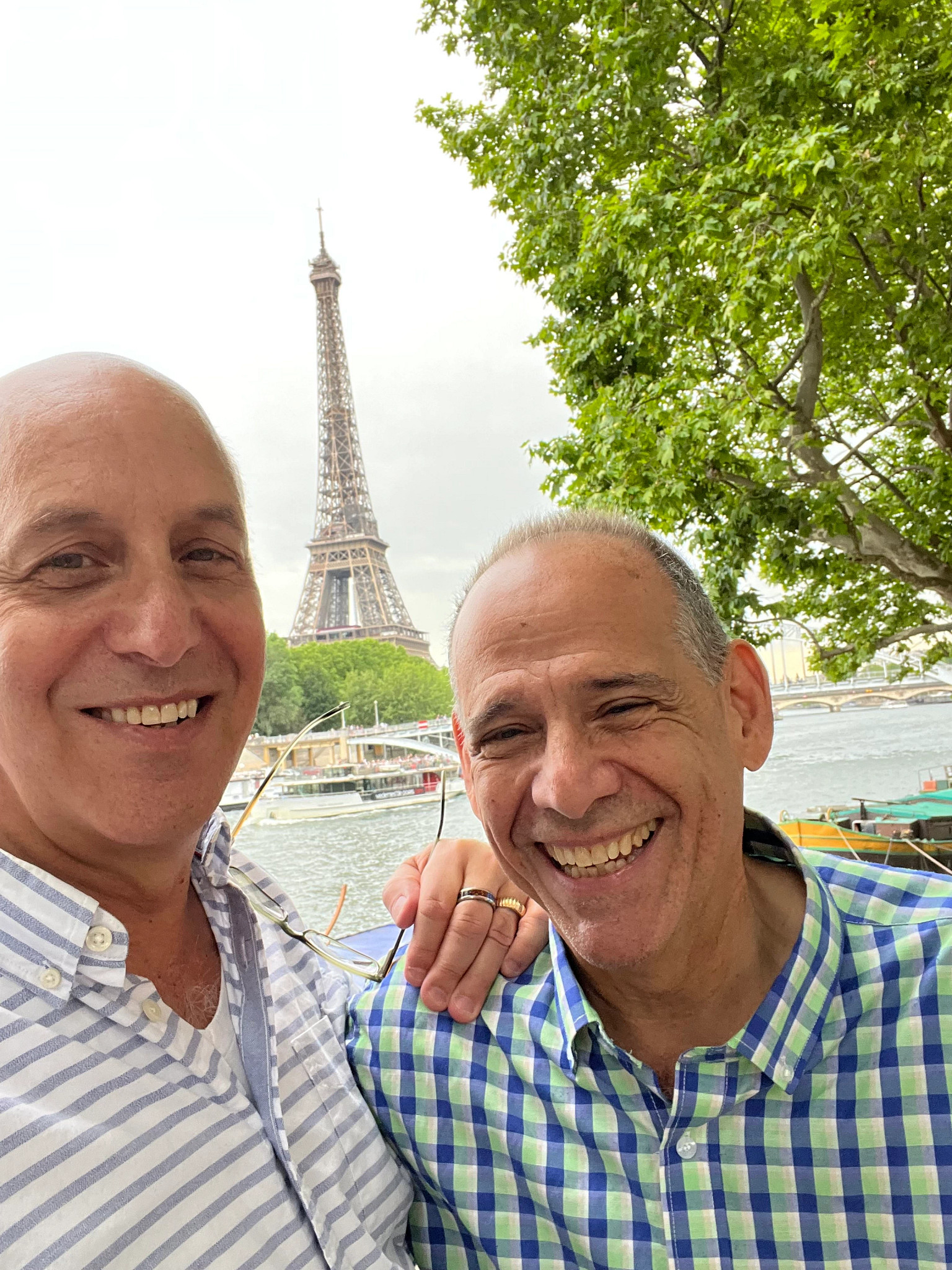 two men standing next to each other and smiling with the eiffel tower in the background