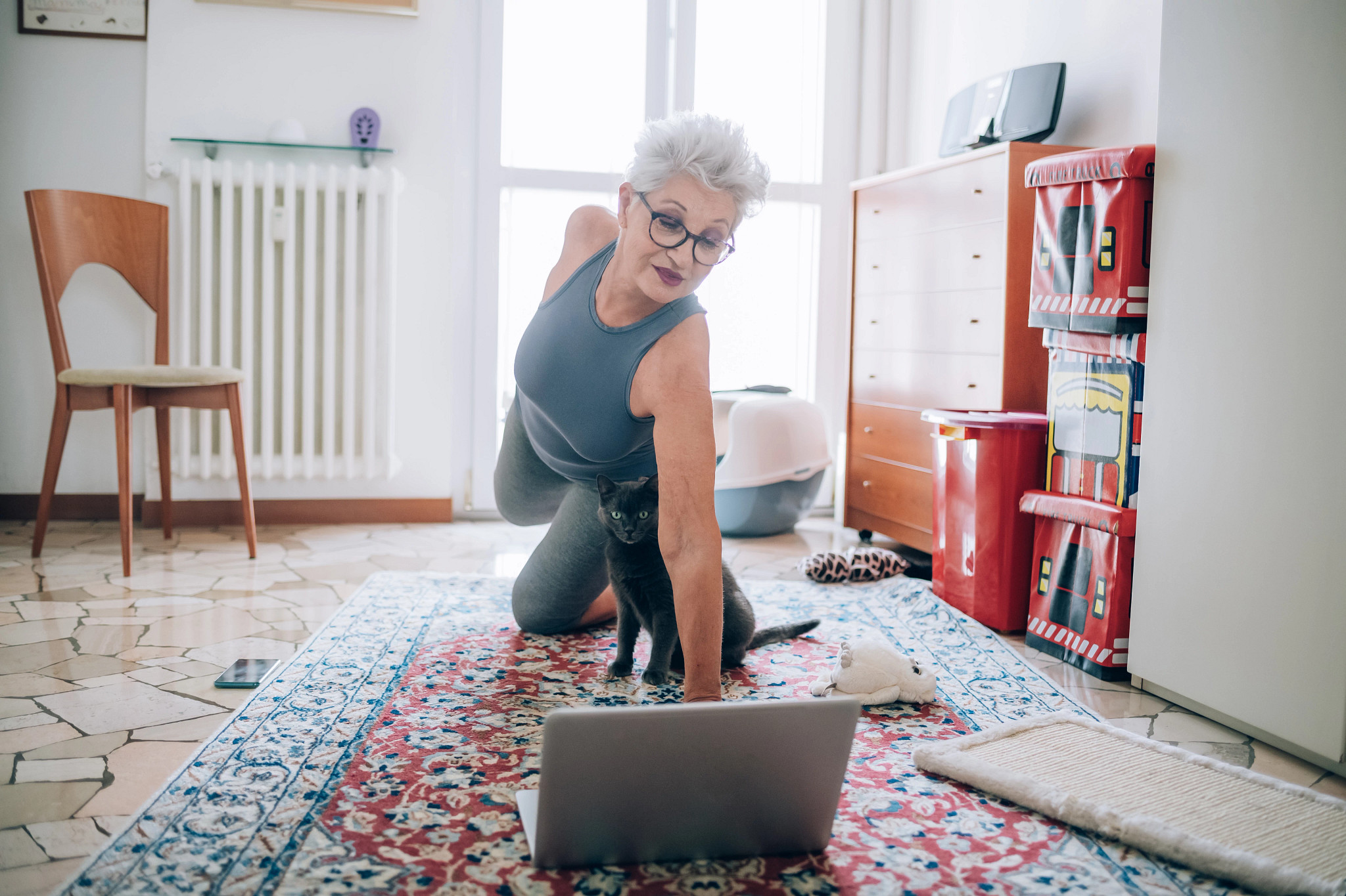 Woman in glasses kneeling on the floor doing yoga pose