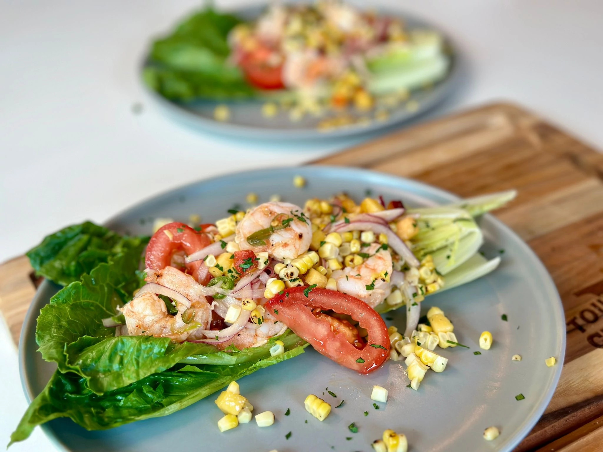 Summer shrimp wedge salad with romaine lettuce, shrimp, corn, tomatoes and onions on plate