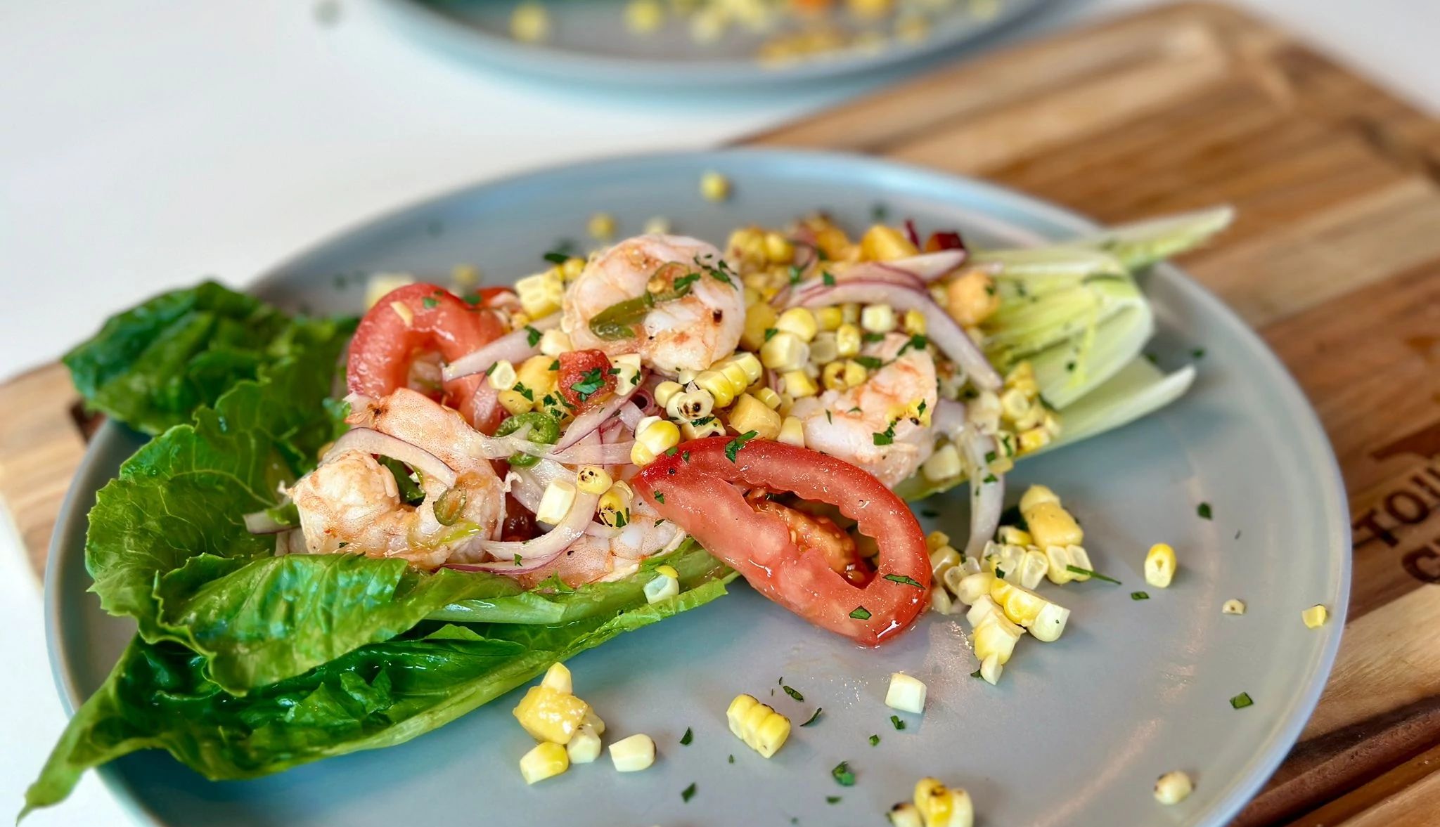 Summer Shrimp Wedge Salad Summer shrimp wedge salad with romaine lettuce, shrimp, corn, tomatoes and onions on plate