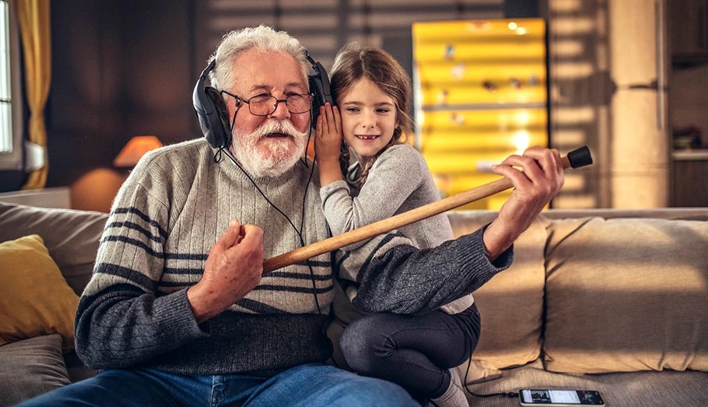 Treating hearing loss can help you stay socially connected as you age A man and girl on a couch listening to music in headphones