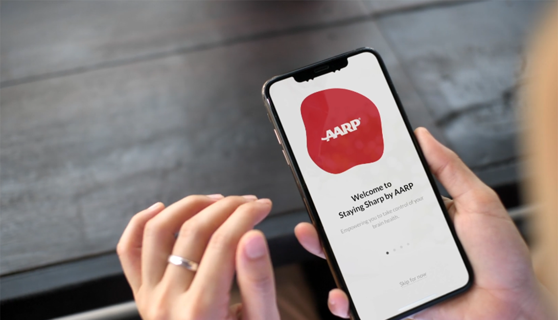 Staying Sharp is an online program from AARP offering content about brain health A woman's hands holding a smartphone with the AARP Staying Sharp app on the screen