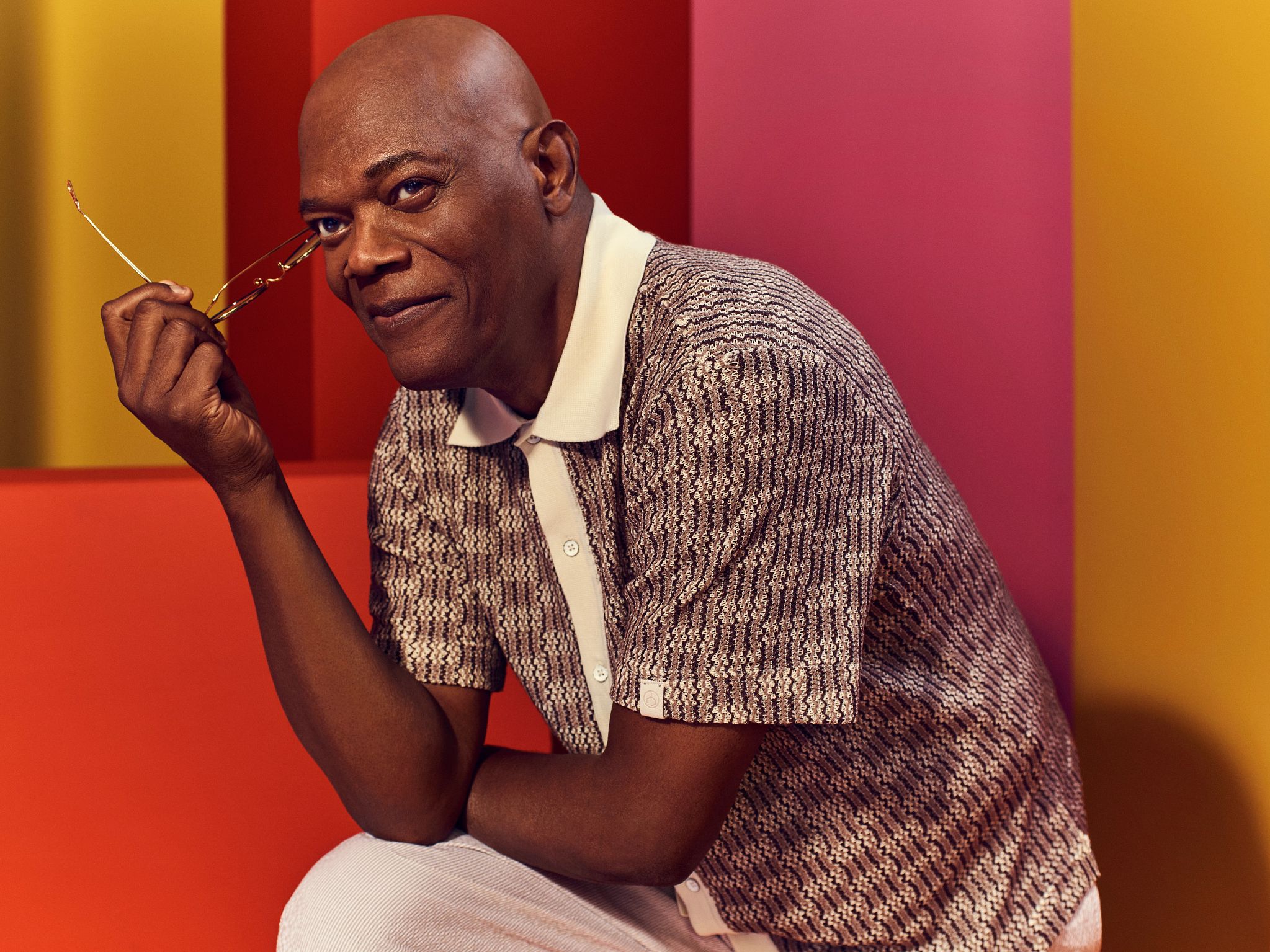 Samuel L. Jackson Samuel L Jackson poses for a portrait placing his elbow to lean on his knee while holding a pair of glasses in his hand