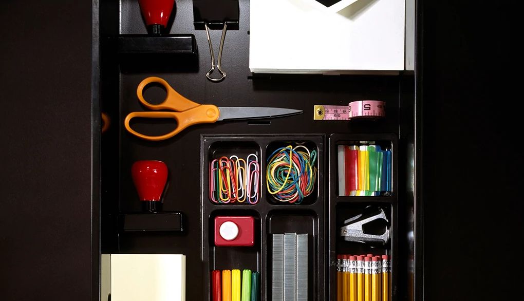 Organizing and decluttering your workspace may help reduce stress An organized desk drawer with pencils, pens, stapler and more