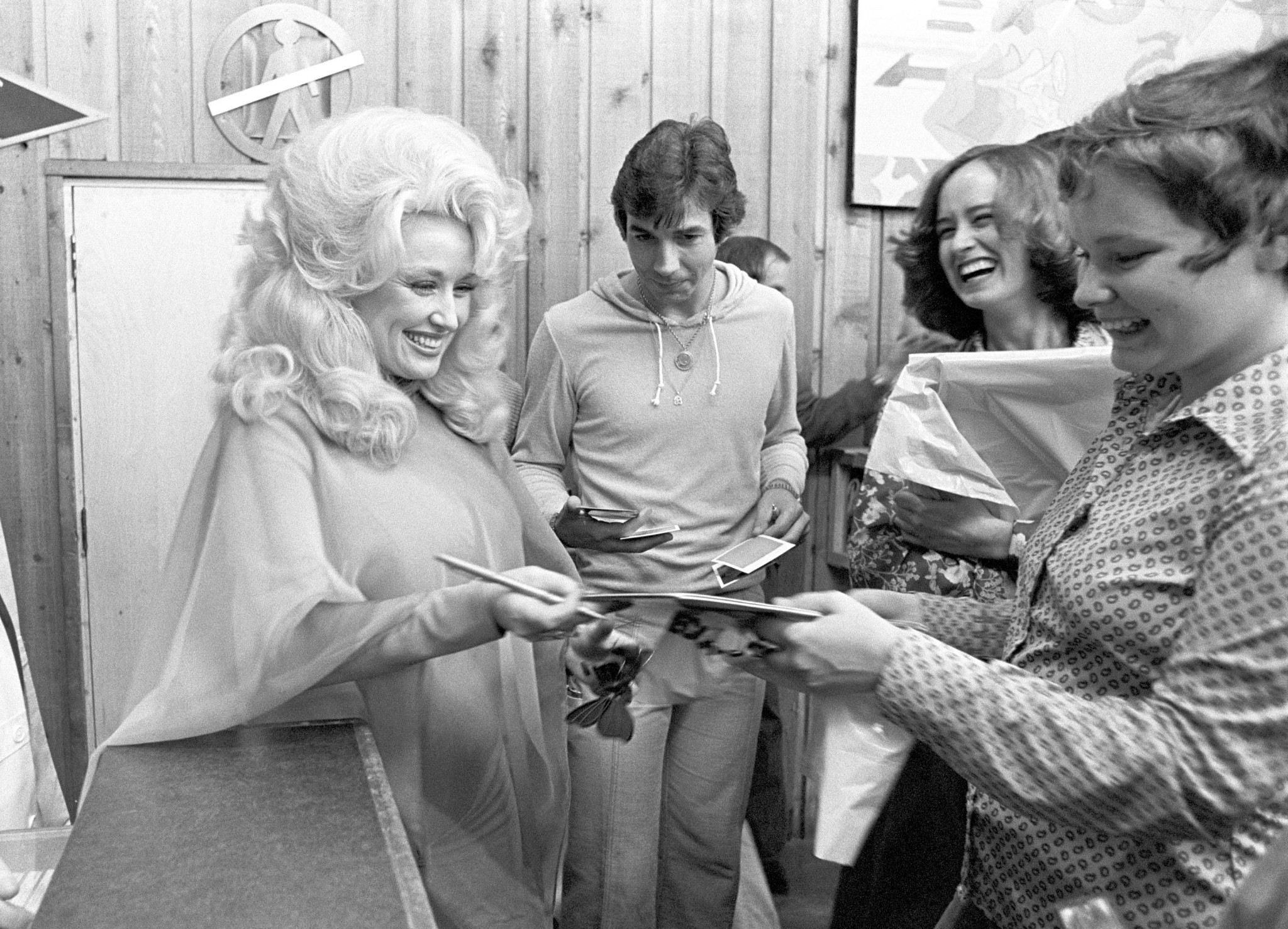 Dolly Parton smiling while greeting fans in a black and white photo