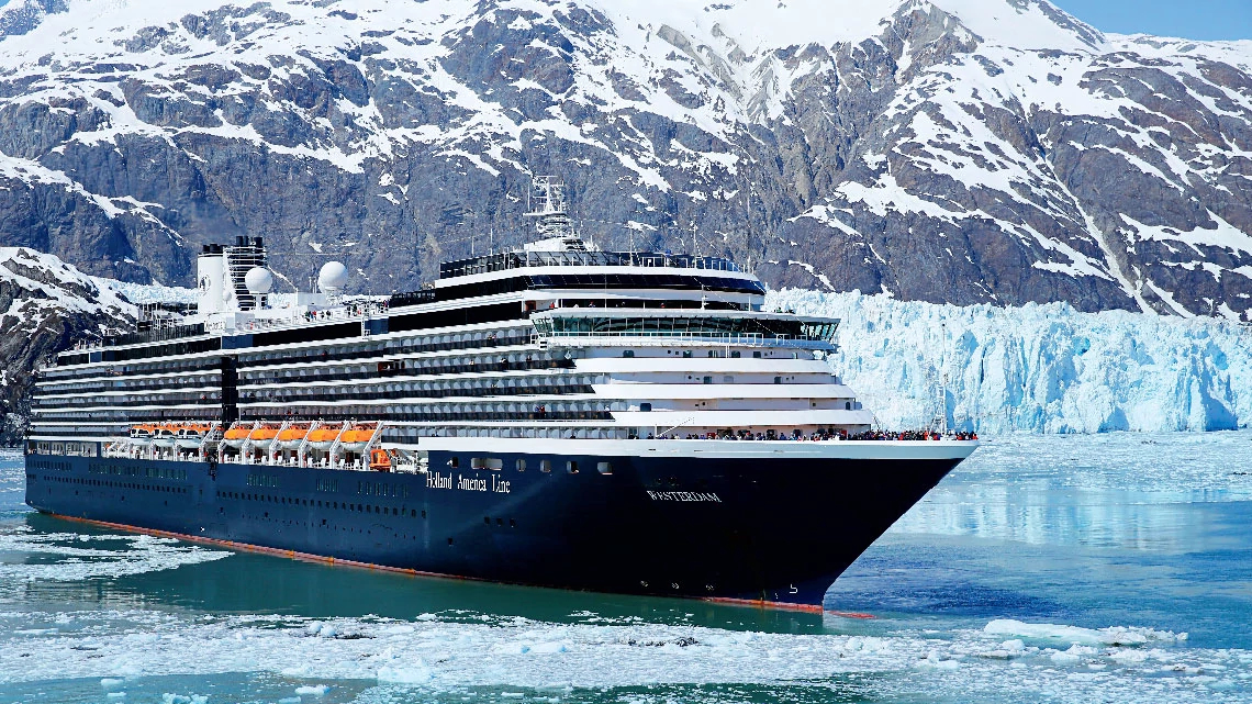 Holland America Line large white and navy cruise ship on icy water with snow-covered mountains and glaciers in the background