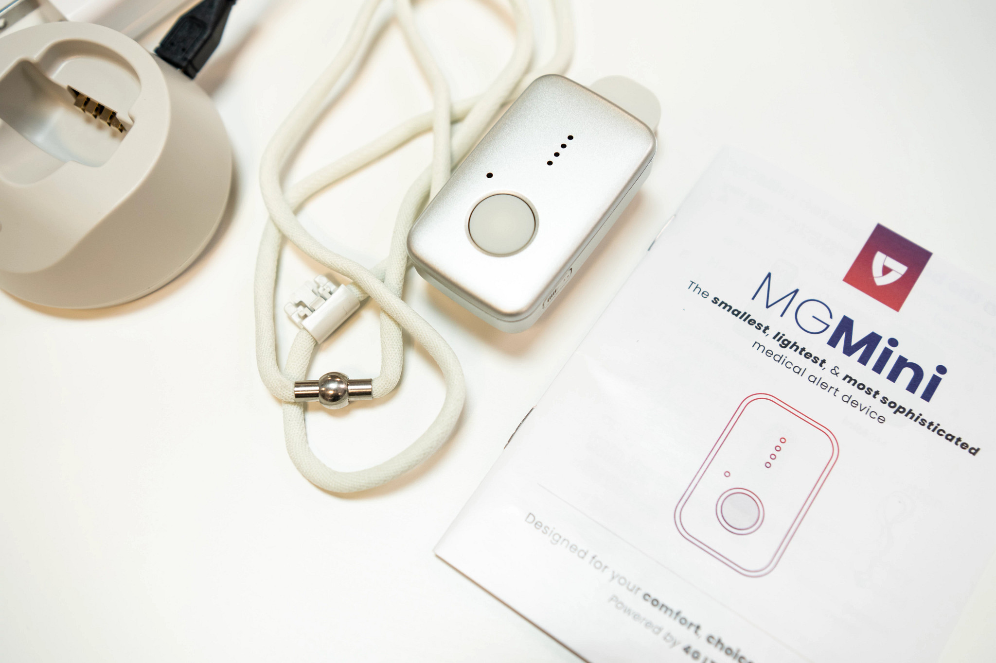The Medical Guardian MG Mini next to the manual on a white table.