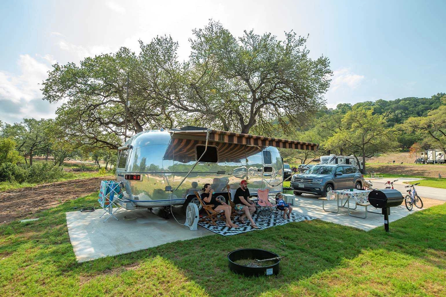 a family sitting in chairs outside a parked RV