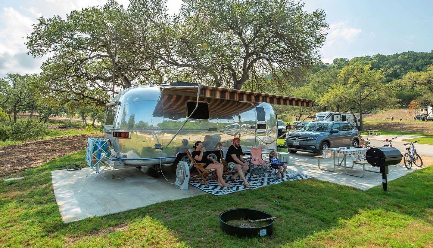Camp Fimfo a family sitting in chairs outside a parked RV