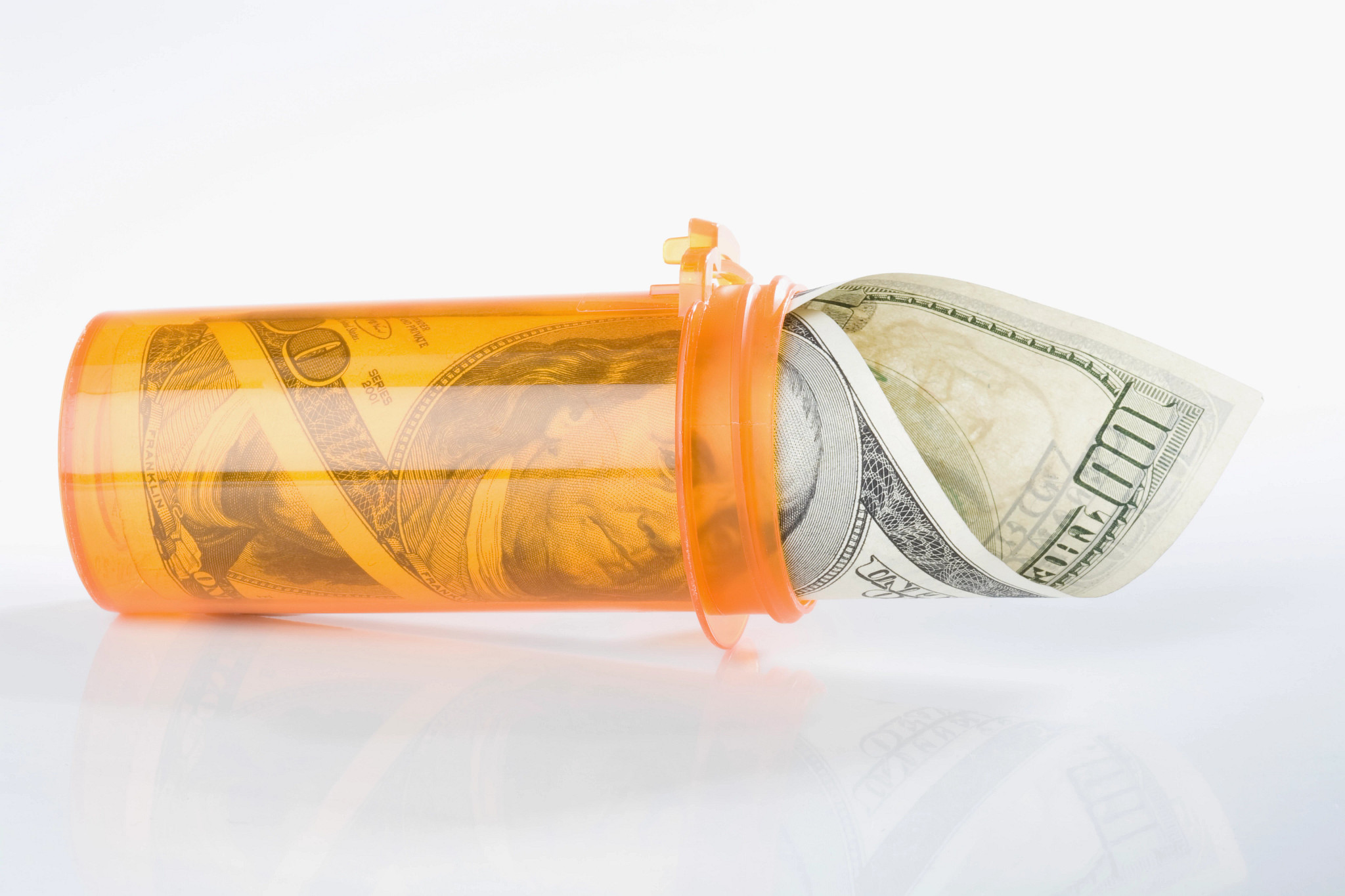 Roll of  US one hundred dollar bills inside a pill bottle
