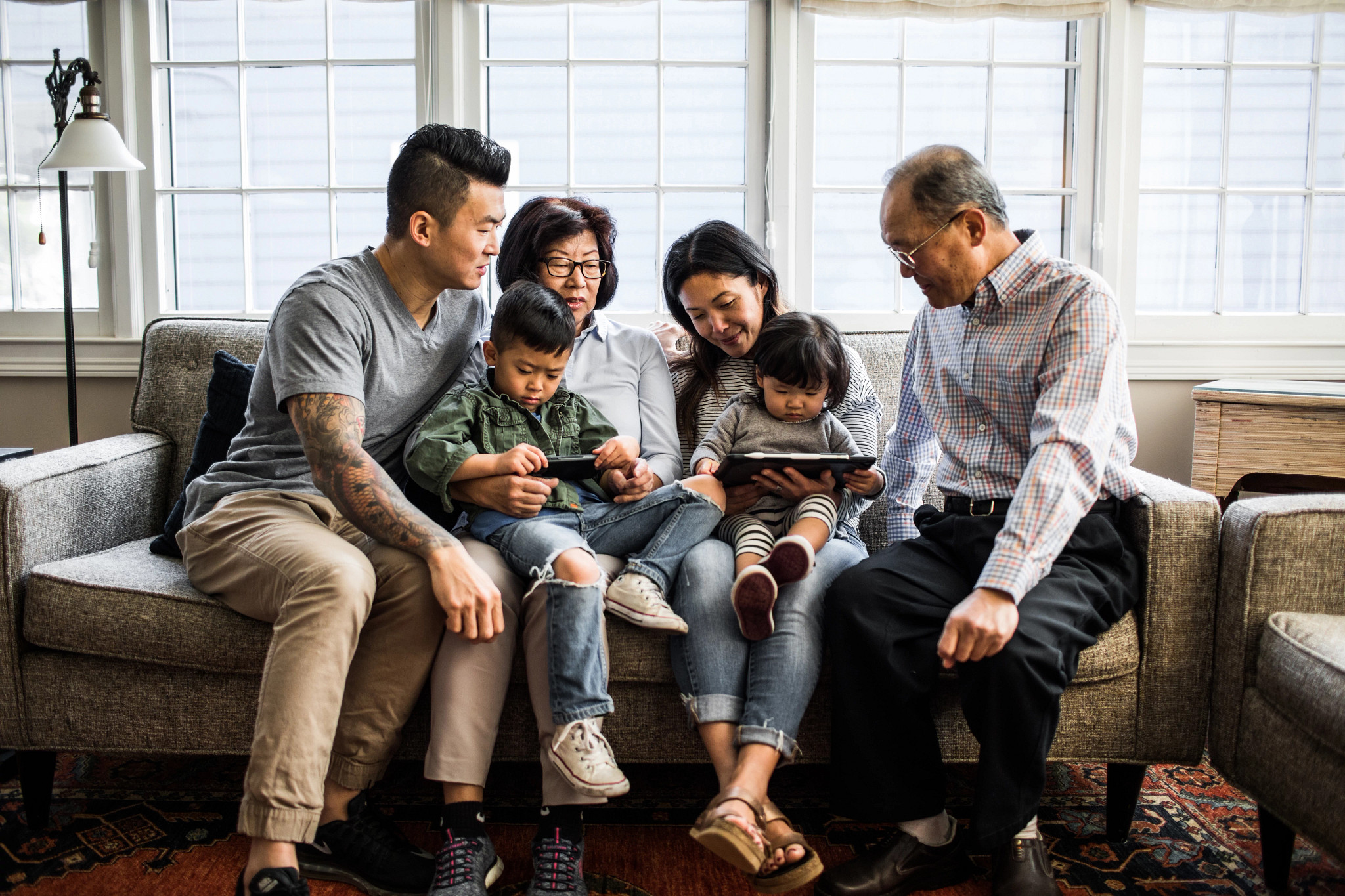 three generations on couch looking at tablet