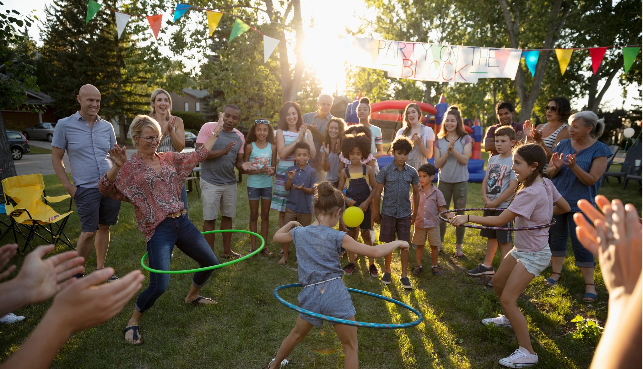 Neighbors spinning in plastic hoops at summer neighborhood block party in park Neighbors spinning in plastic hoops at summer neighborhood block party in park