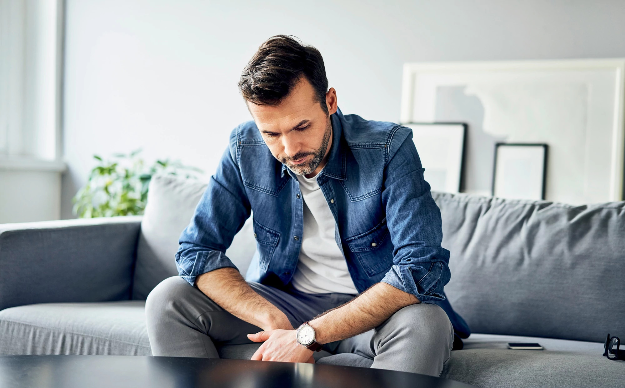 Depressed man sitting at home on the couch