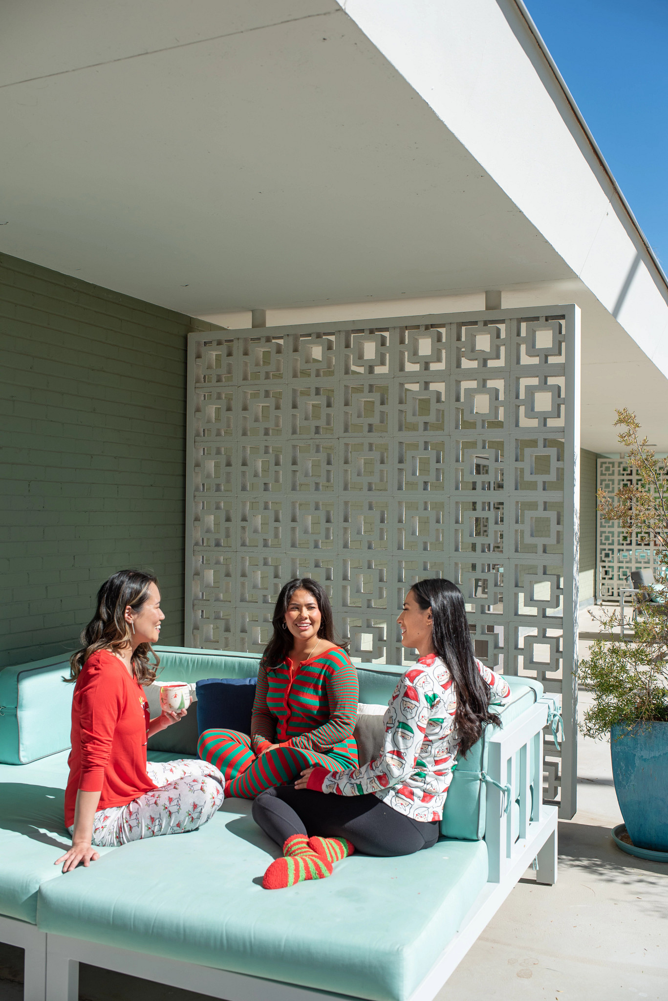 three women wearing festive pajamas sitting and talking on a hotel patio