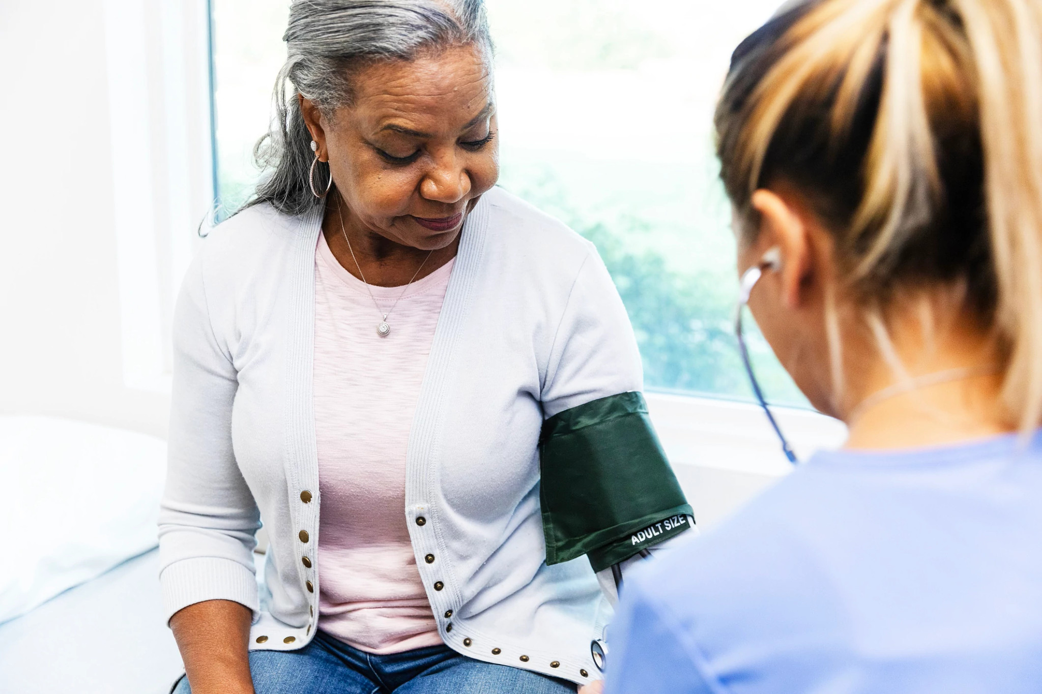 woman watches as  female nurse checks her blood pressure