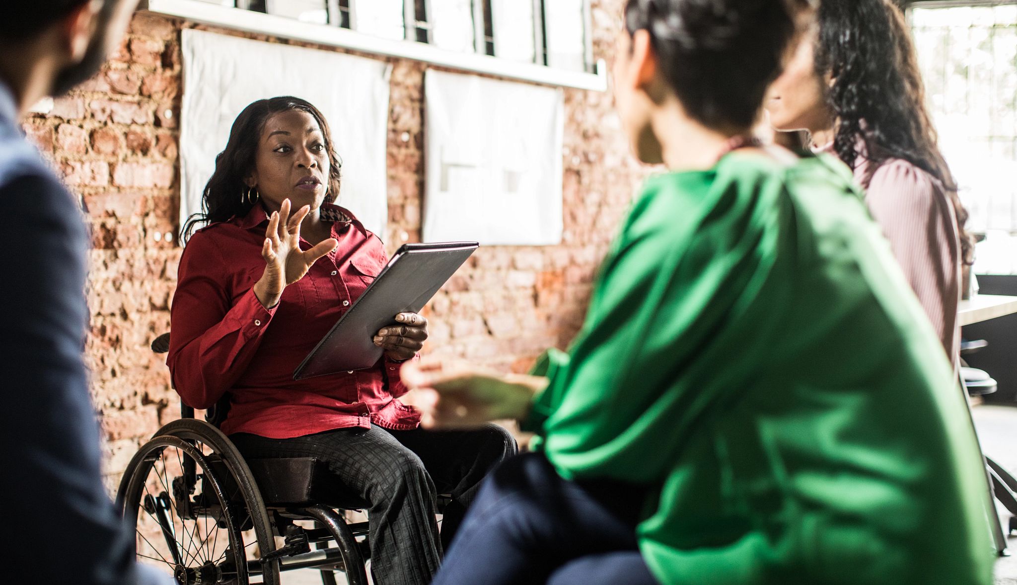 Businesswoman in wheelchair leading group discussion in creative office Businesswoman in wheelchair leading group discussion in creative office