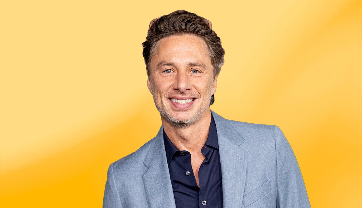 actor zach braff smiling for a portrait in front of a yellow background