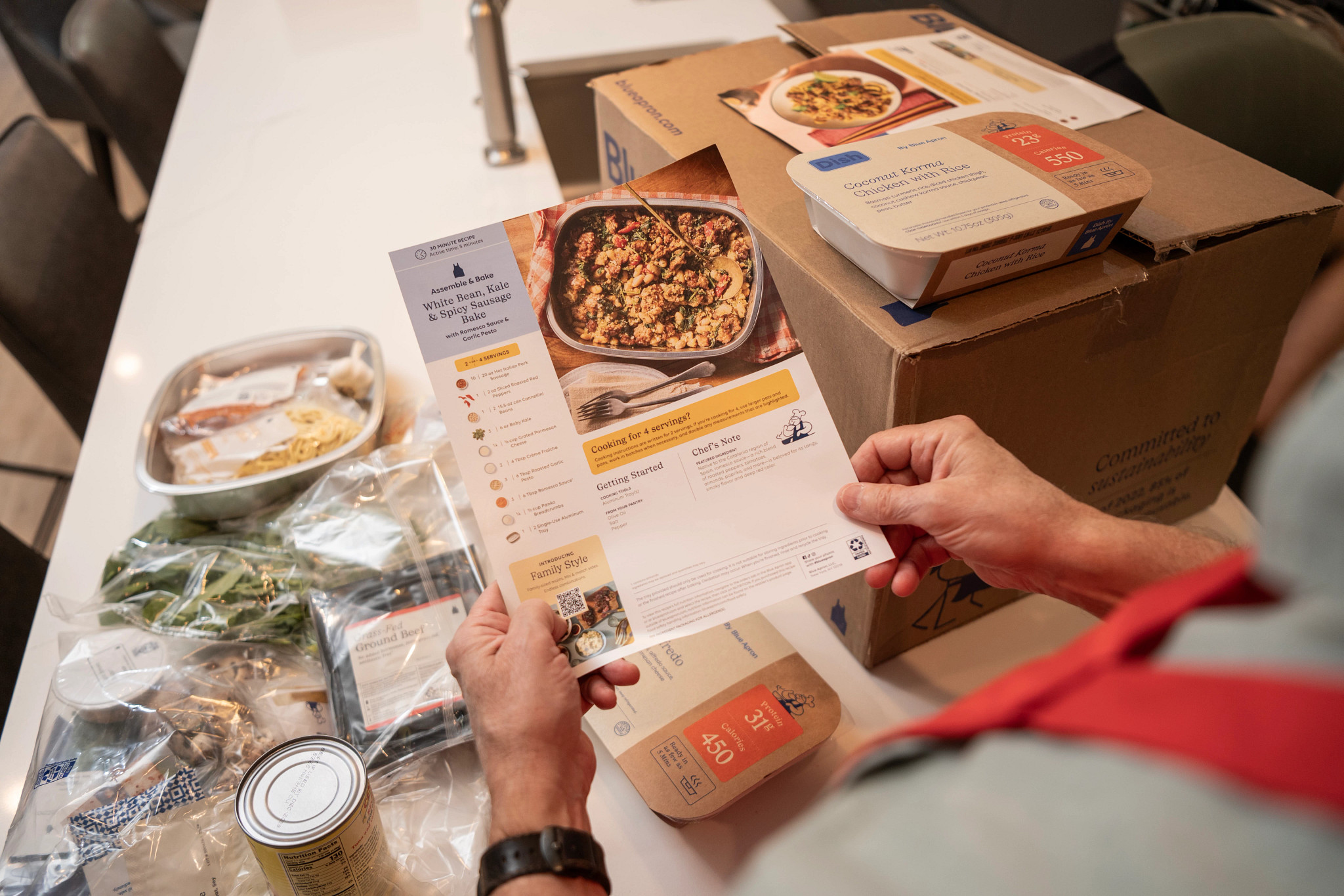 A man reading the recipe card of a Blue Apron meal.