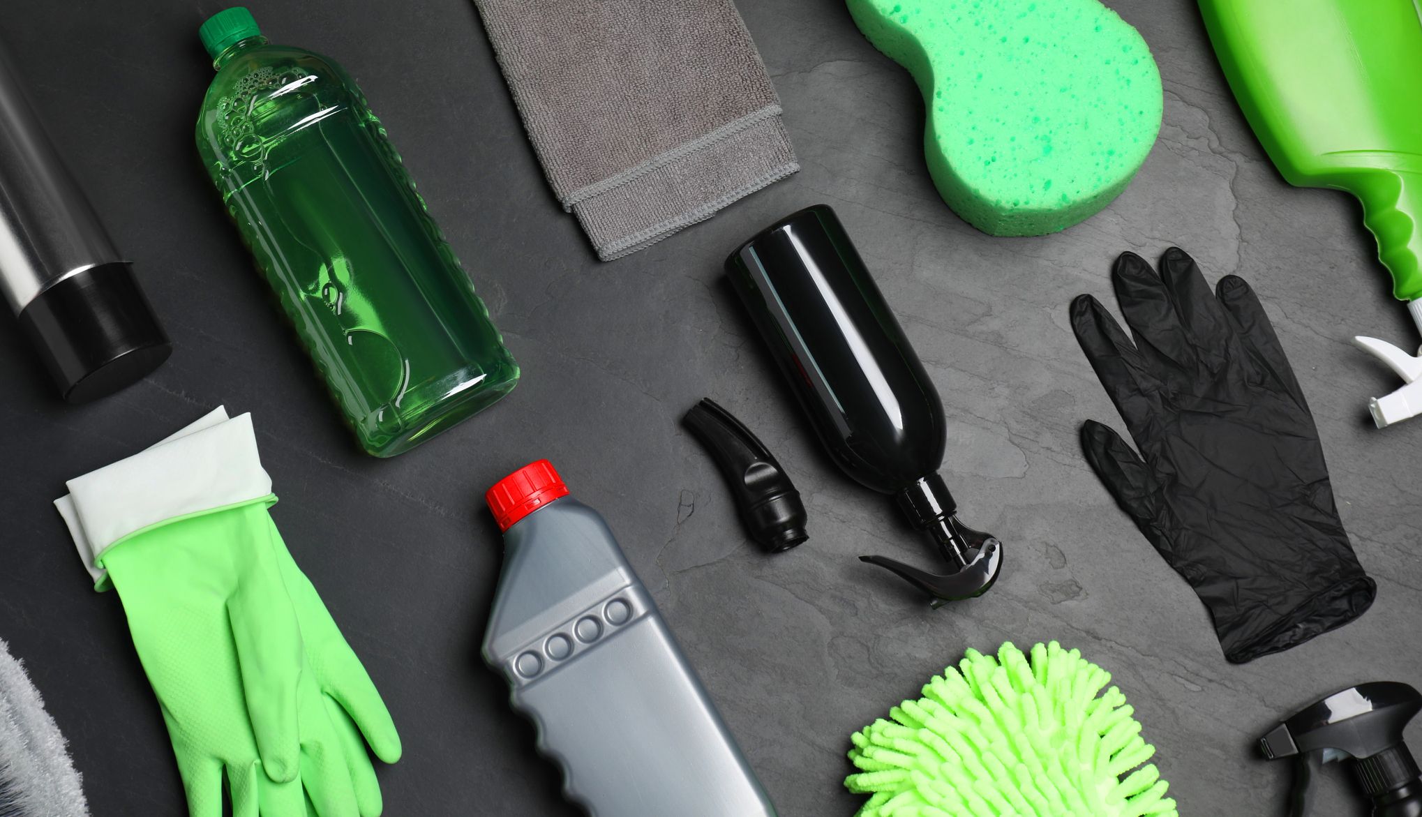 The basics to car cleaning Towel, sponge, gloves, bottle of cleaner on grey table
