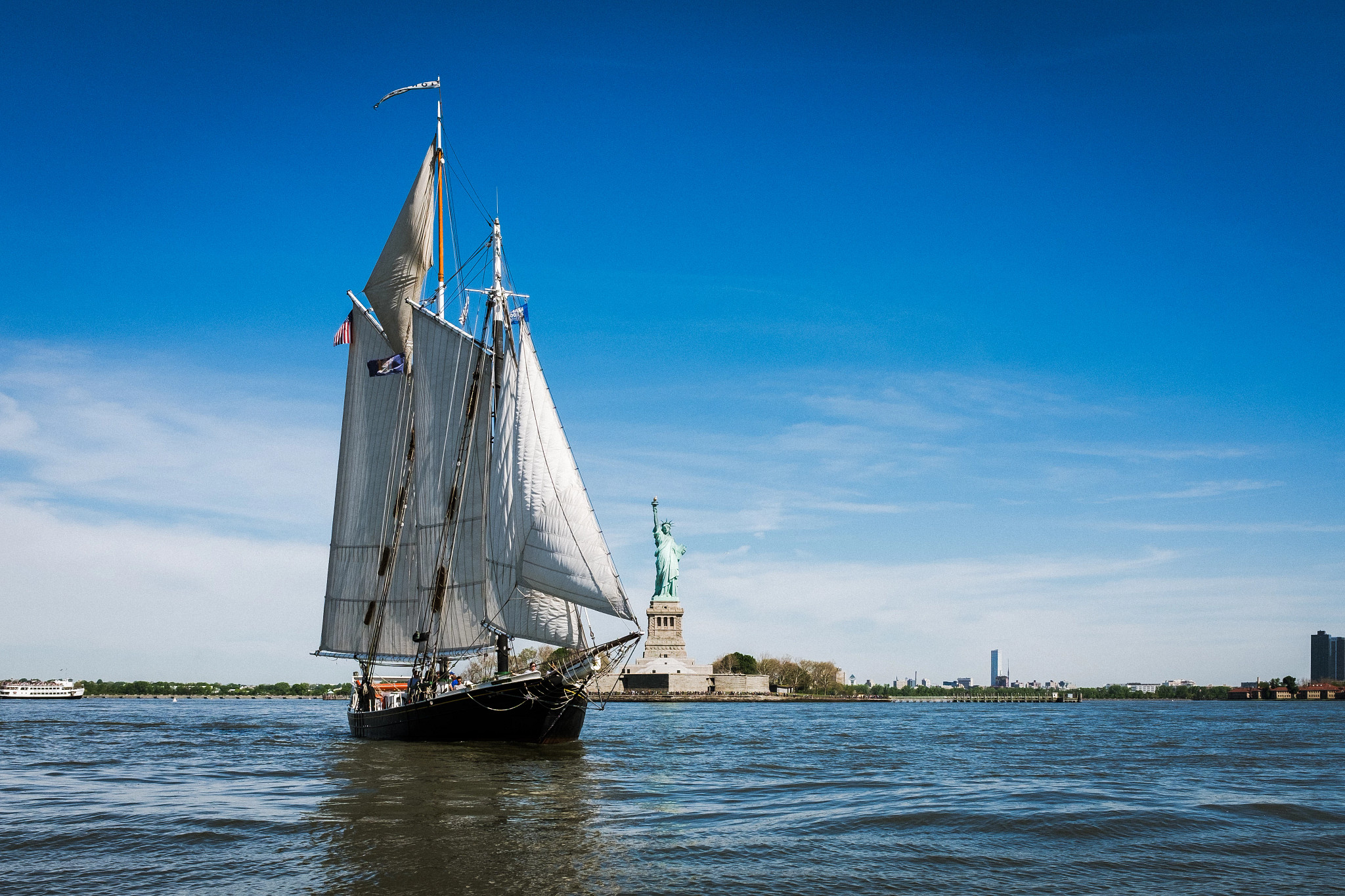 a sail boat in the Hudson River near the Statue of Liberty