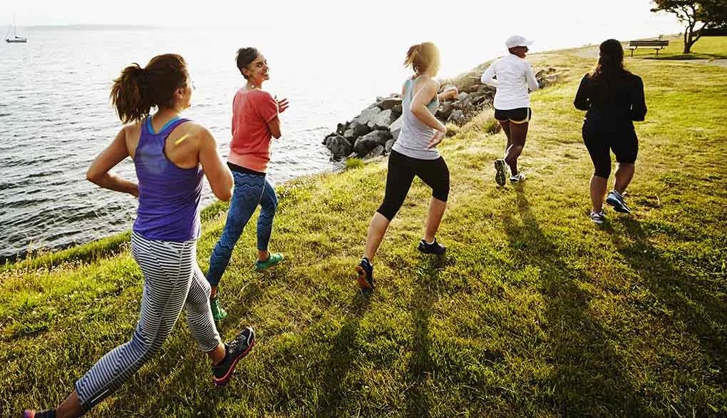 Exercise is a habit that supports your brain health A group of women running on grass by a body of water