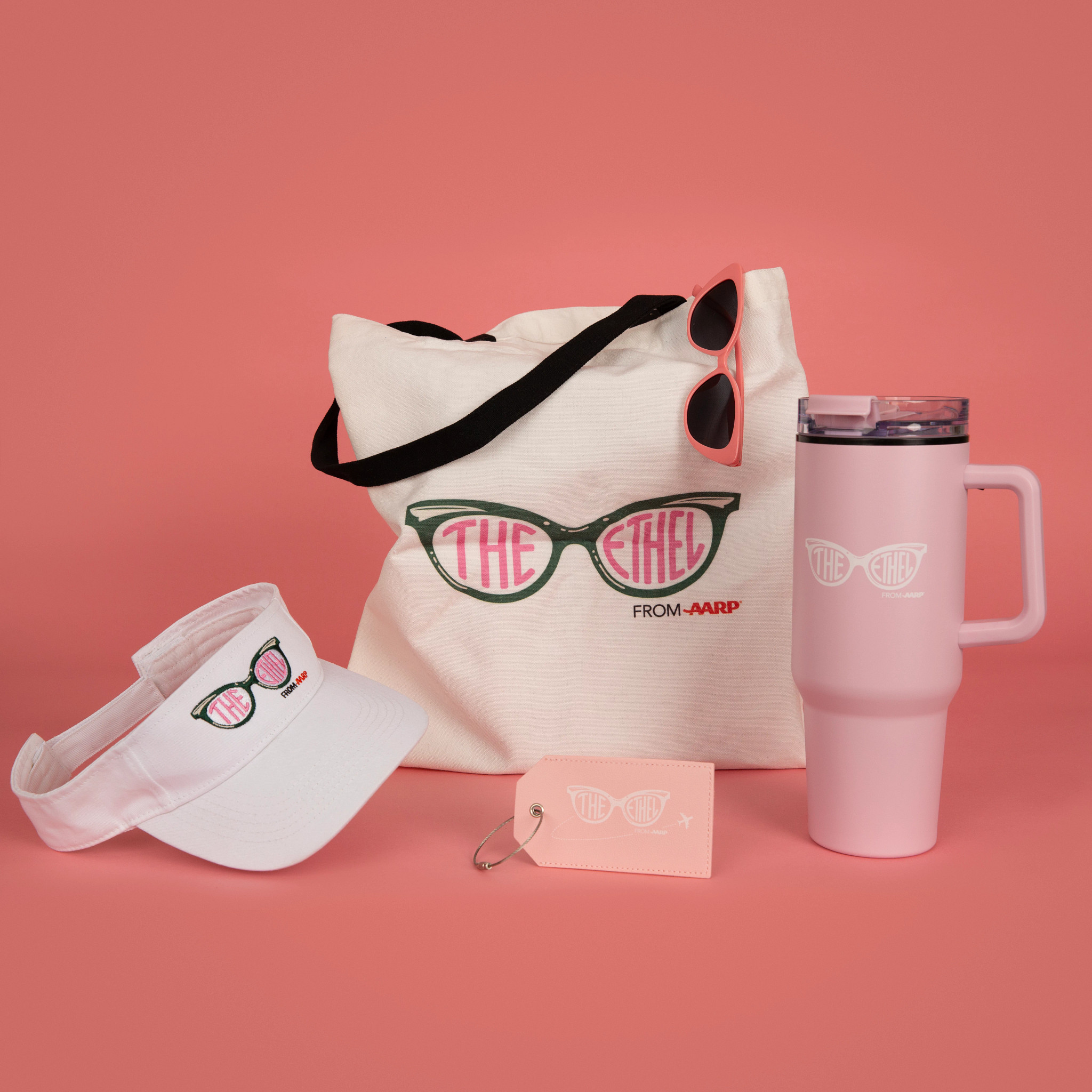 Group of Ethel branded products including a logo tote bag, reusable tumbler, sunglasses, luggage tag, and visor displayed together on a clean background.