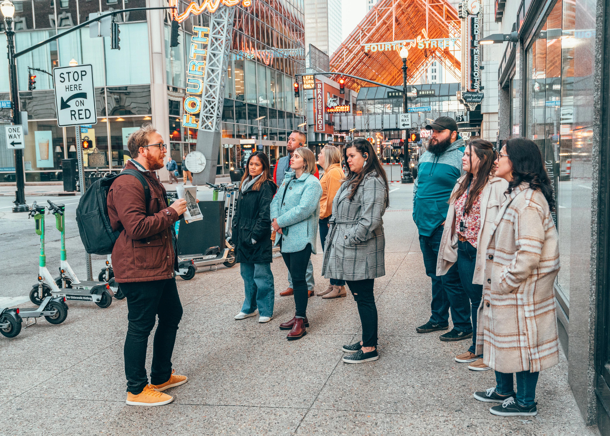 a guide talks to people standing on a sidewalk during a tour
