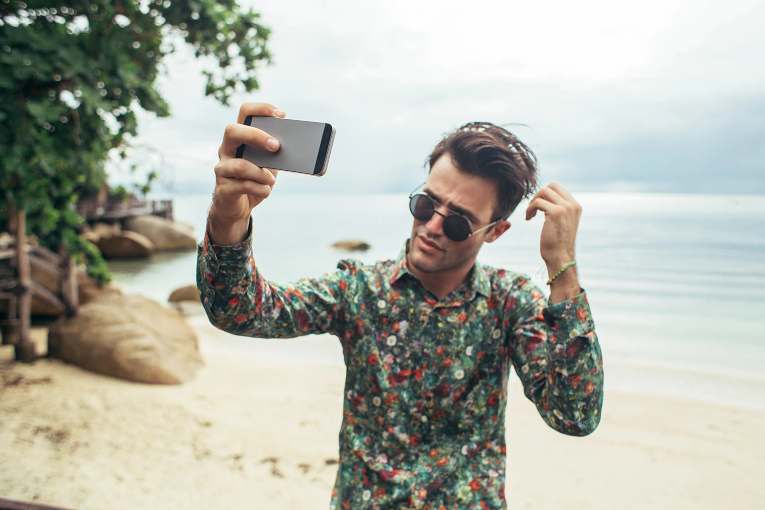 Narcissistic man taking photo of himself on the beach with his phone. 