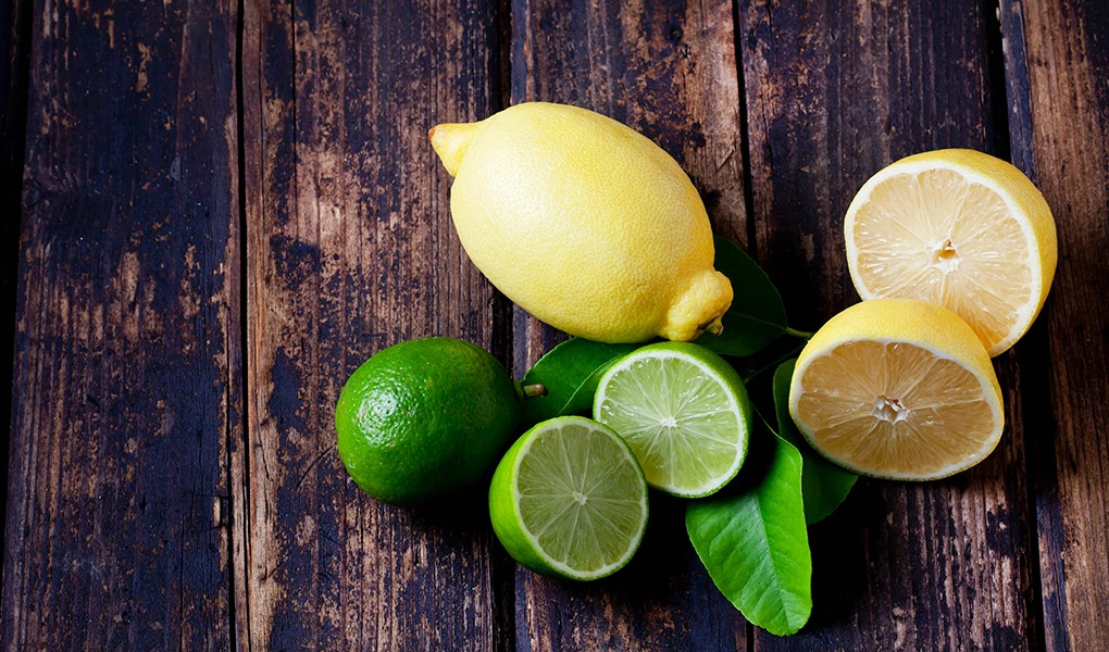 A close-up view of lemons and limes on dark wood
